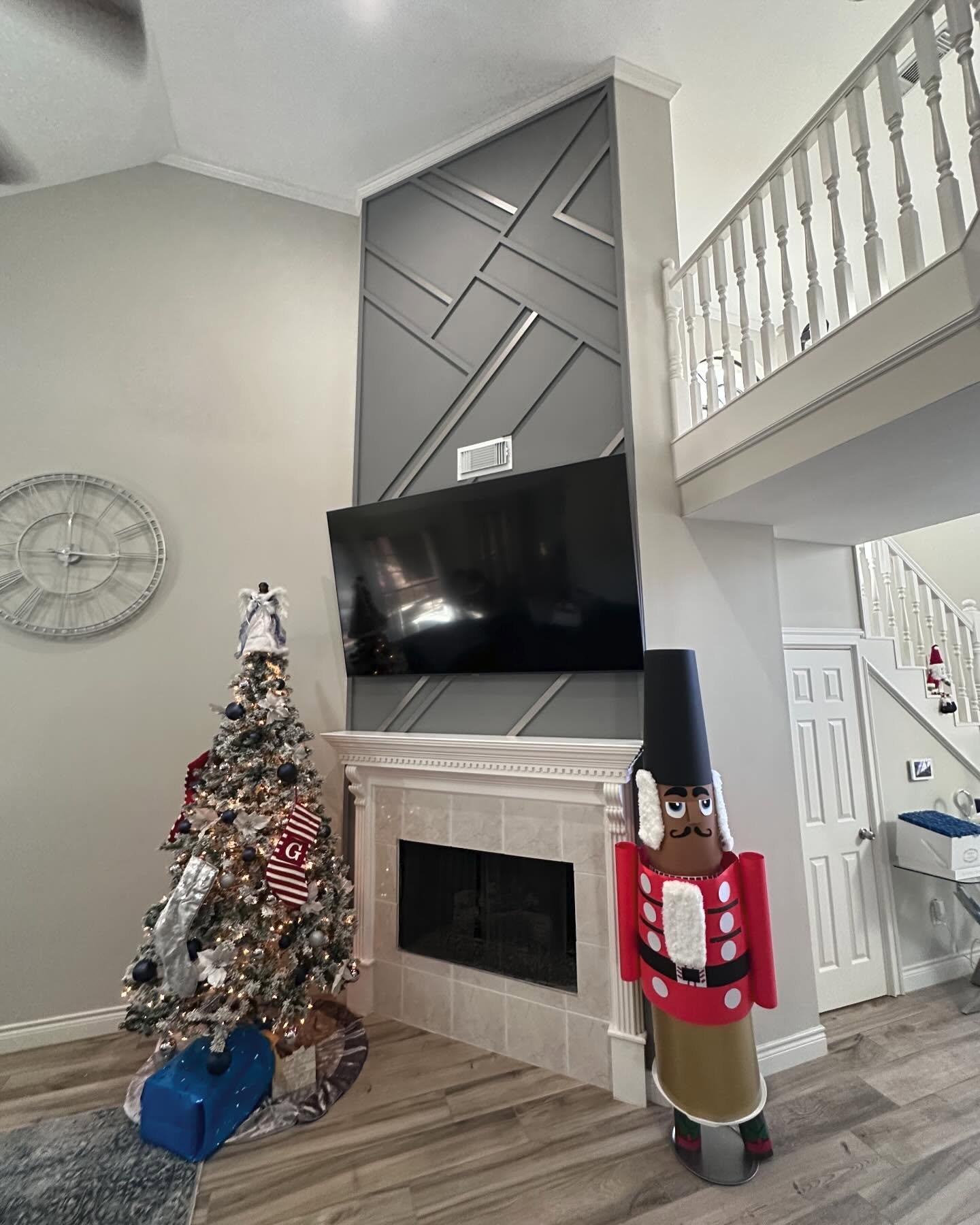 Living room with a high ceiling featuring a fireplace and a dark gray geometric wood trim accent wall above the mantel.