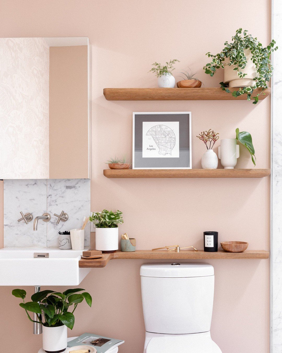Light oak floating shelves with rounded corners on a pink wall