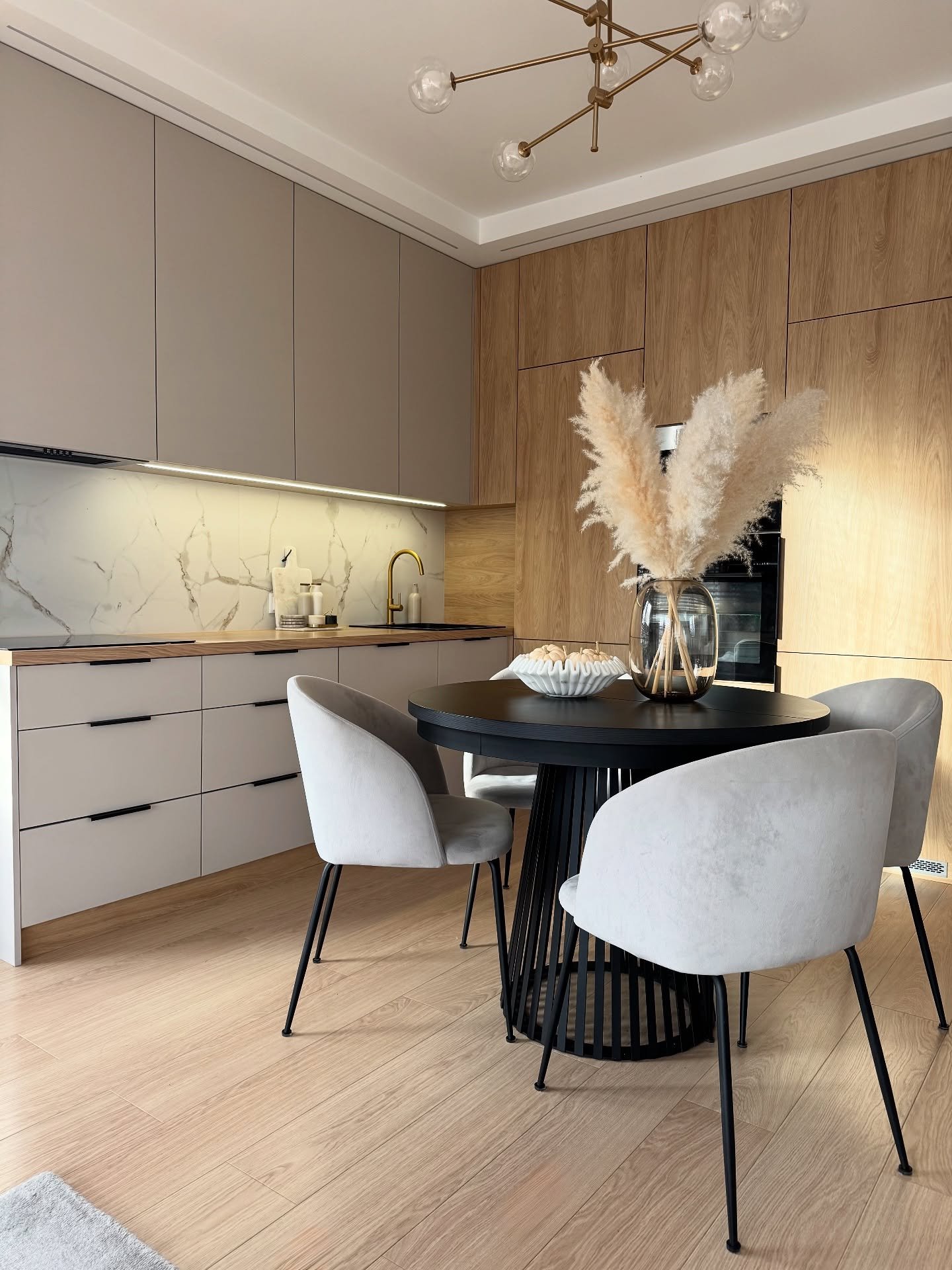 Round black kitchen table with slatted cone base and grey velvet chairs