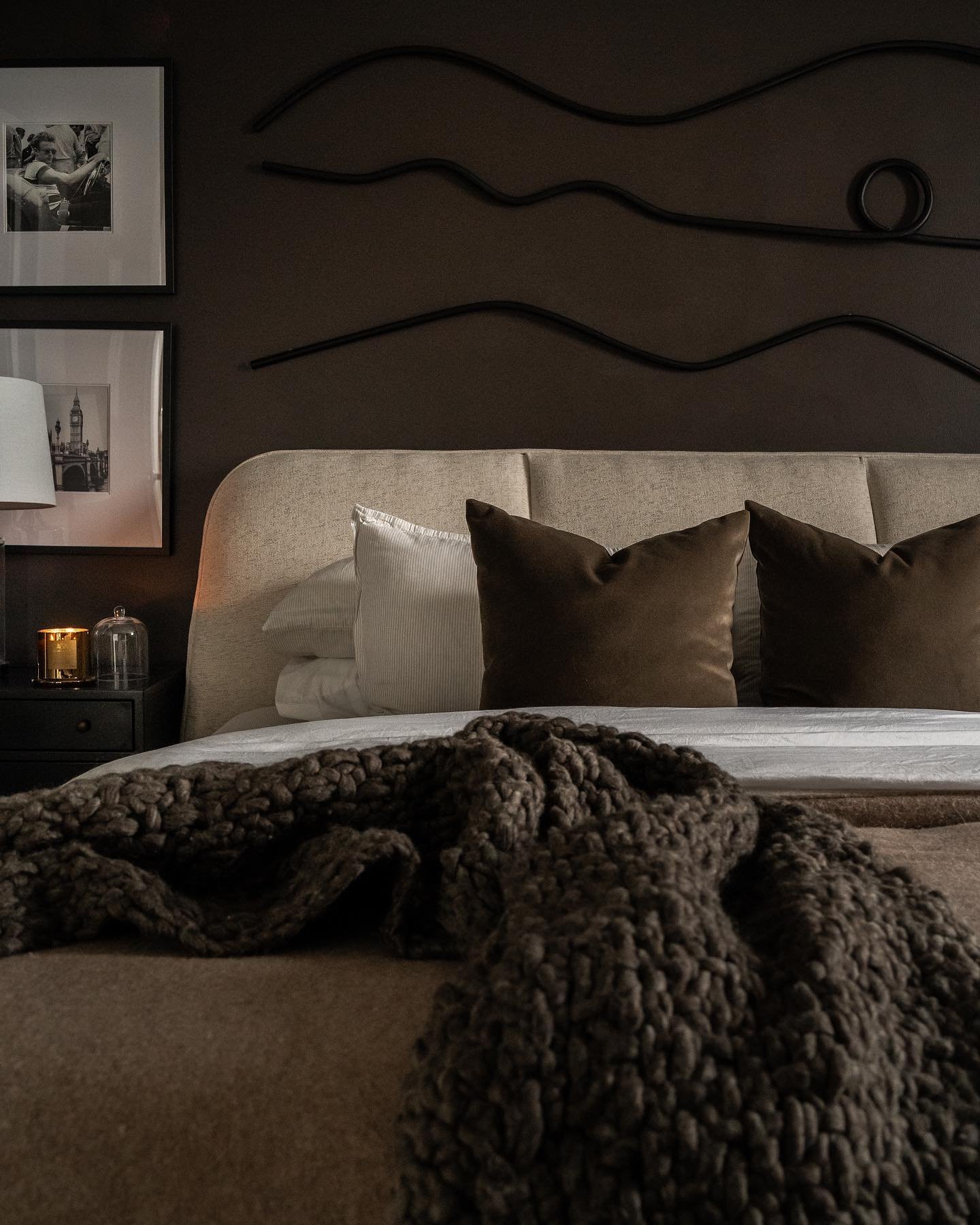 Brown bedroom with wavy black wall art and chunky knit throw