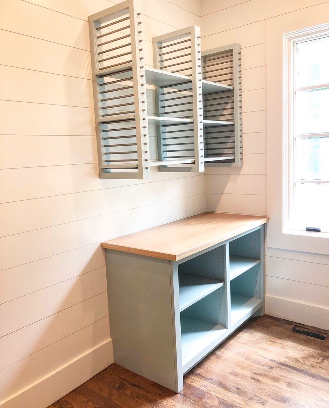 Blue wall-mounted drying rack shelves and base cabinet open shelving in a laundry room
