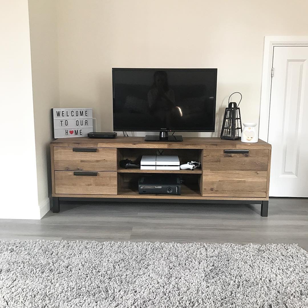 Wooden TV stand with black metal legs and game consoles