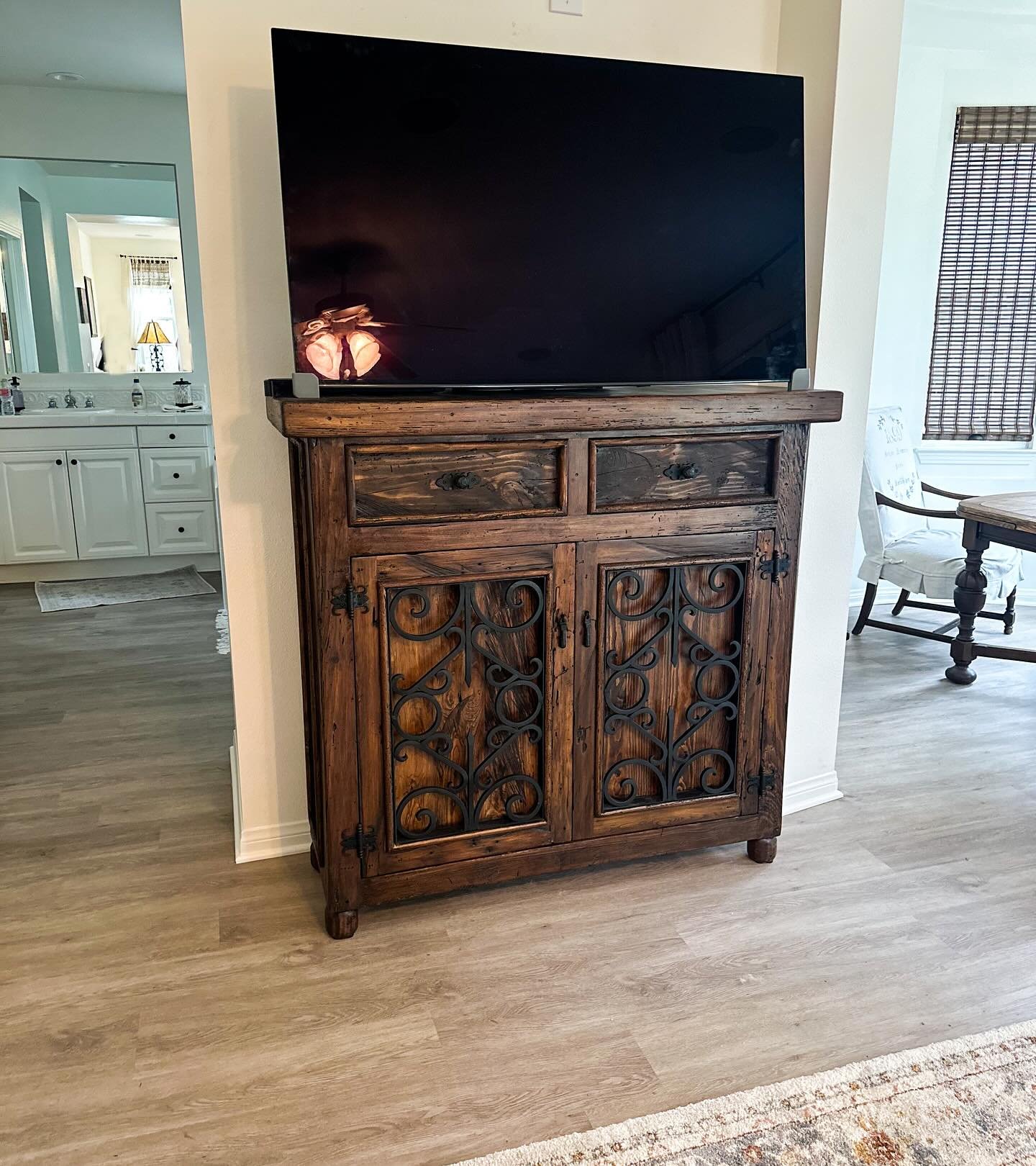 Tall dark wood TV cabinet with iron scrollwork on cabinet doors