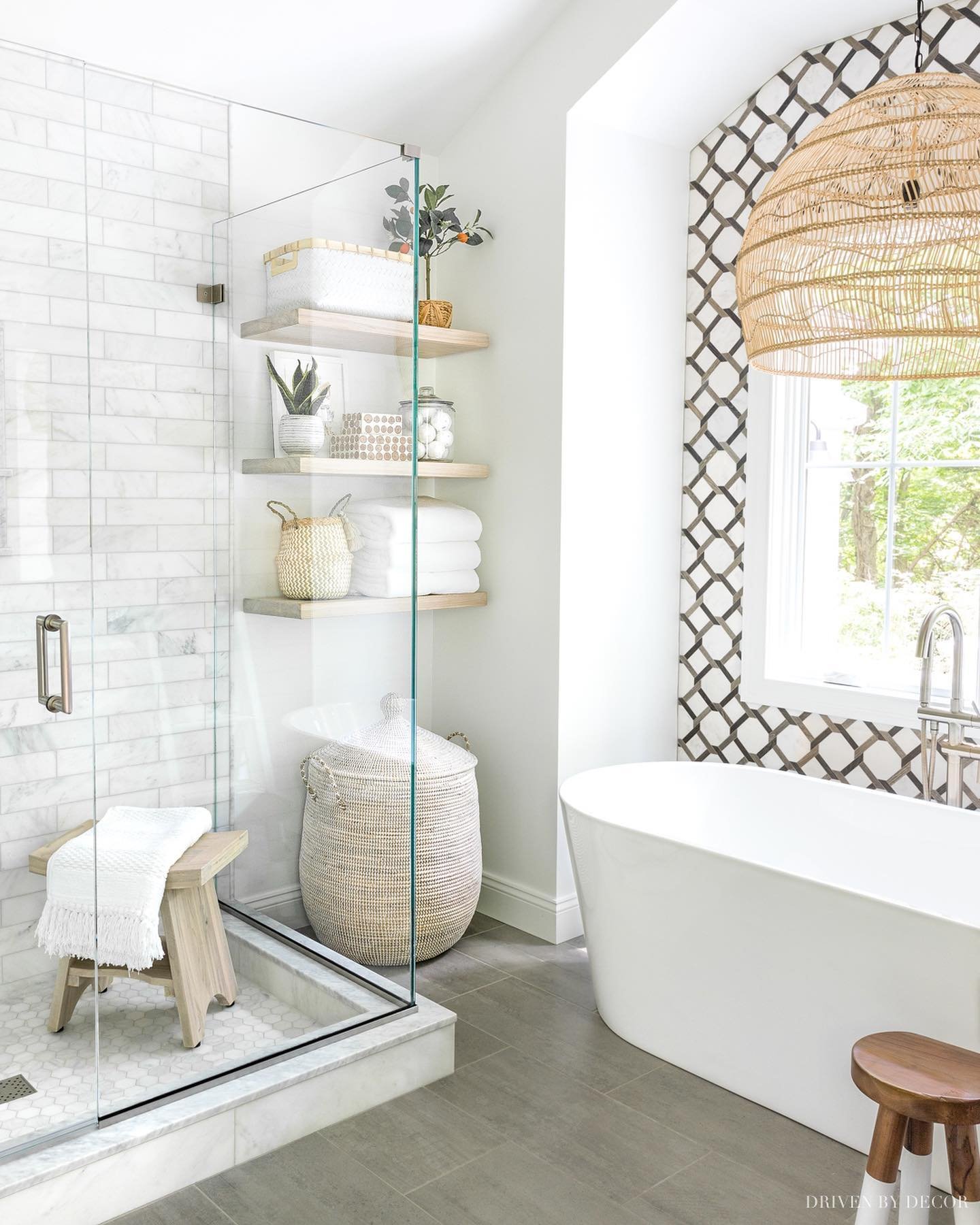 Light-colored floating shelves built into a nook beside a glass shower, holding towels and storage baskets.