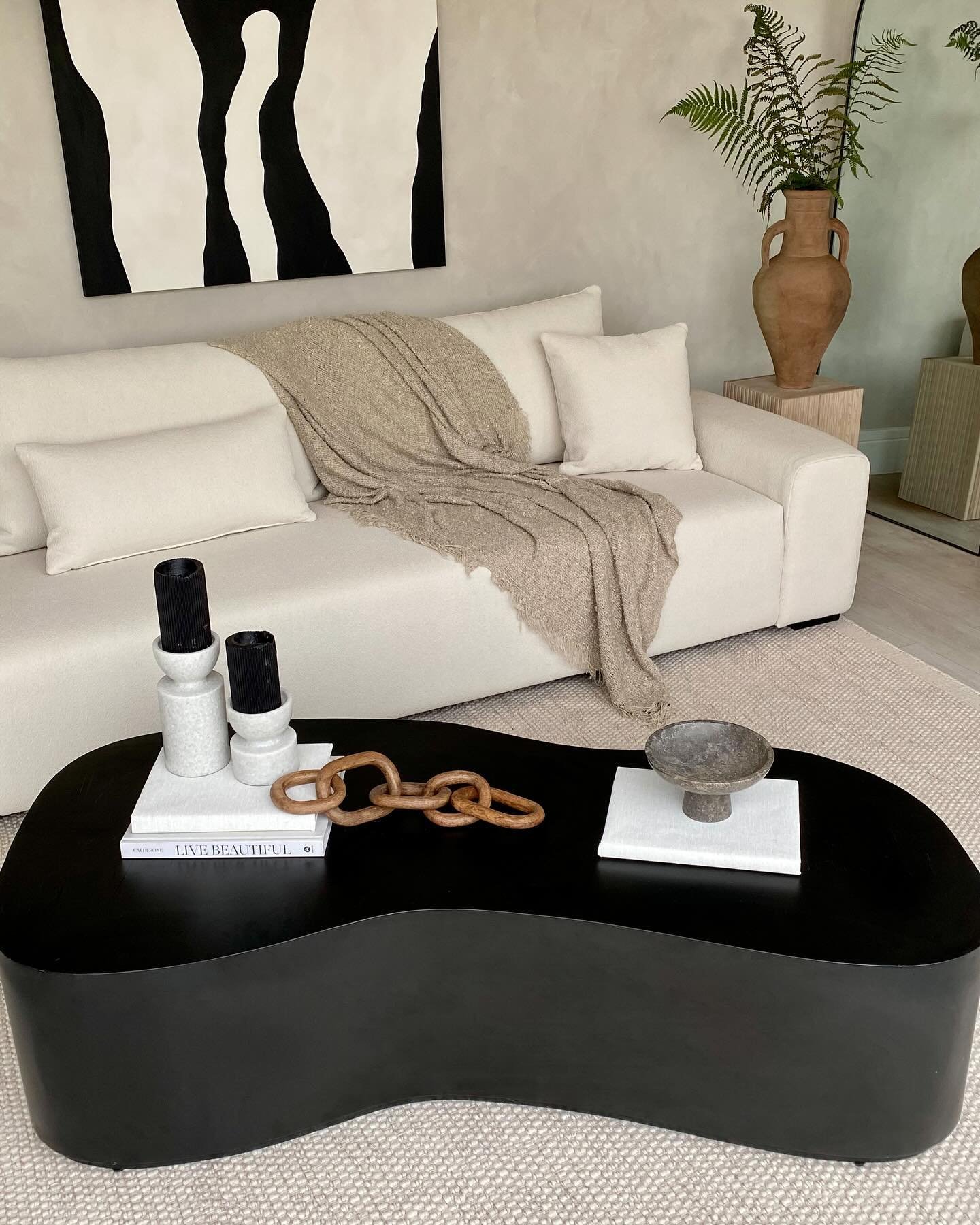 Black kidney shaped coffee table block in a neutral modern living room