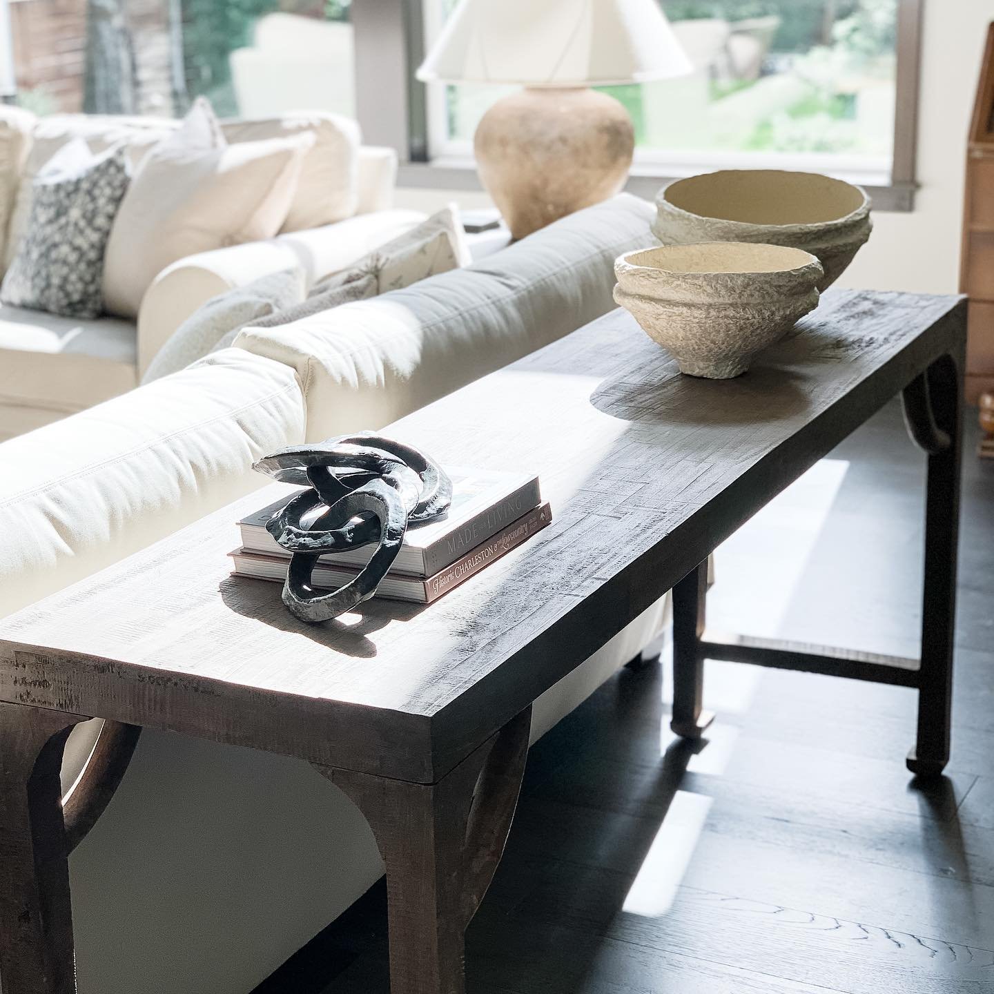 Dark weathered wood console table with curved leg details behind a sofa