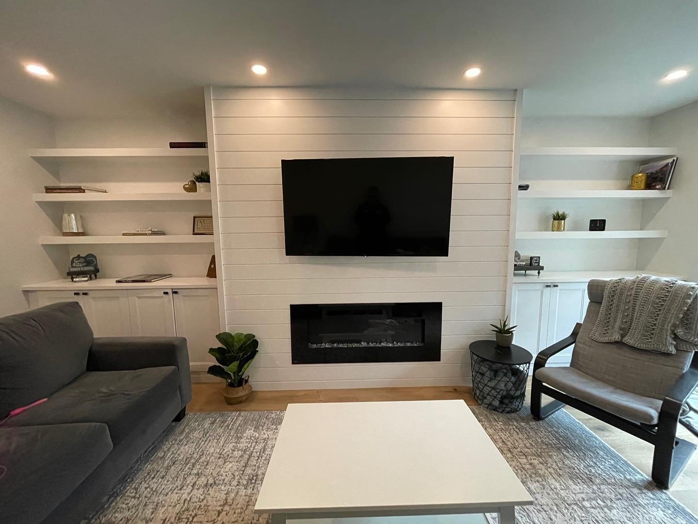 White shiplap fireplace wall with symmetrical floating shelves and a linear electric fire.