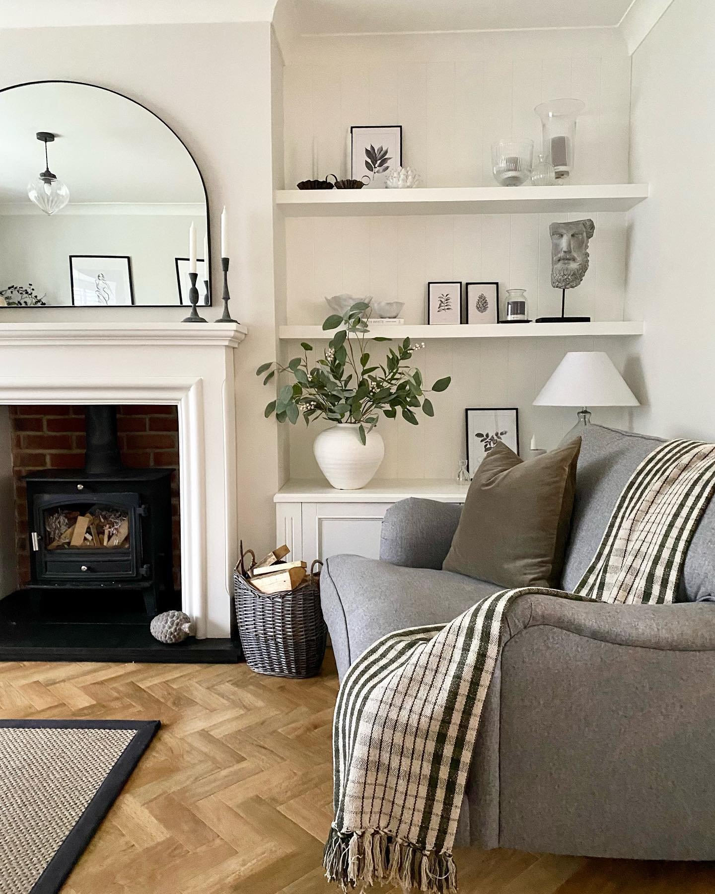 White floating alcove shelves with monochrome decor next to a brick fireplace.