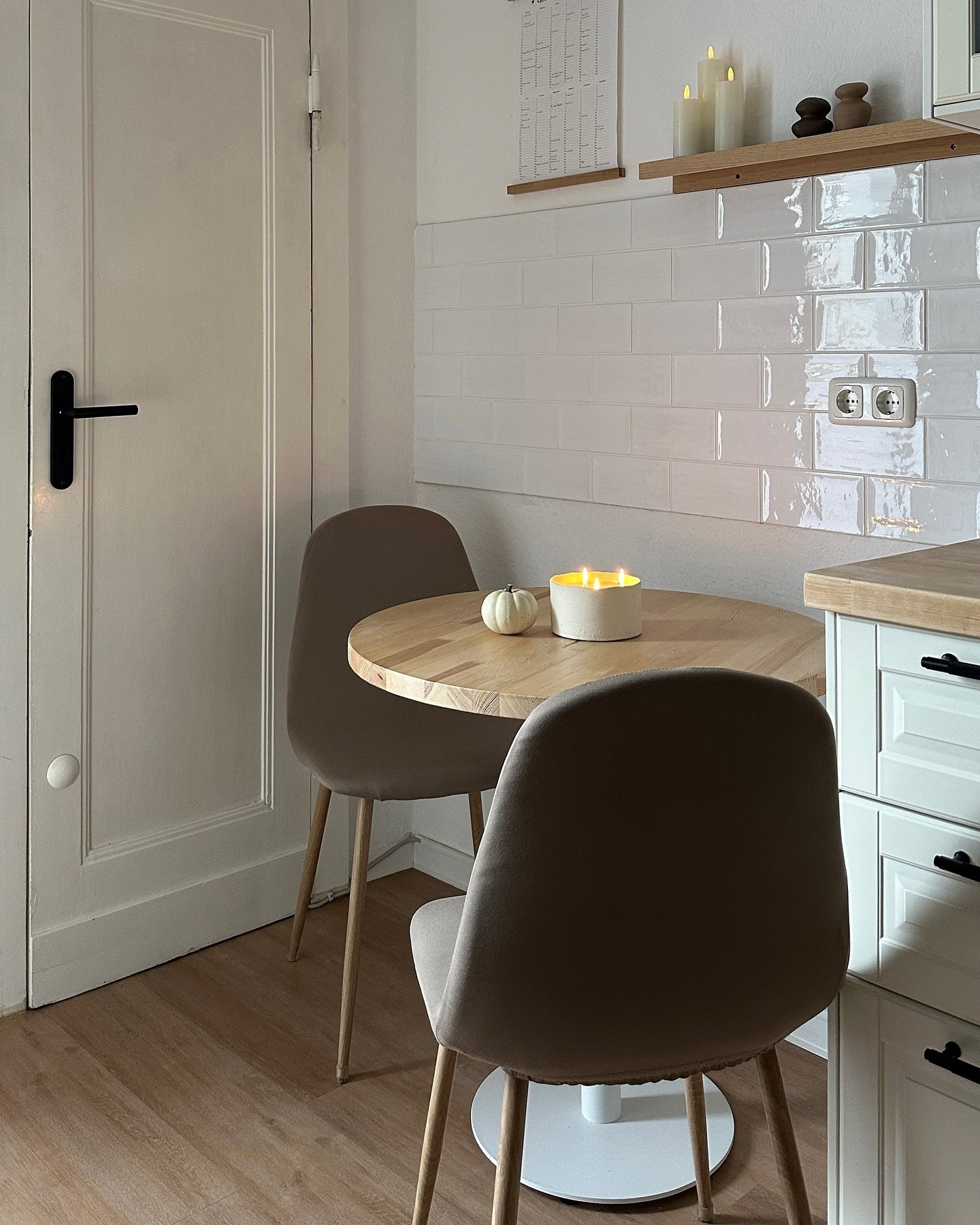 Small round butcher block table with white pedestal base in corner