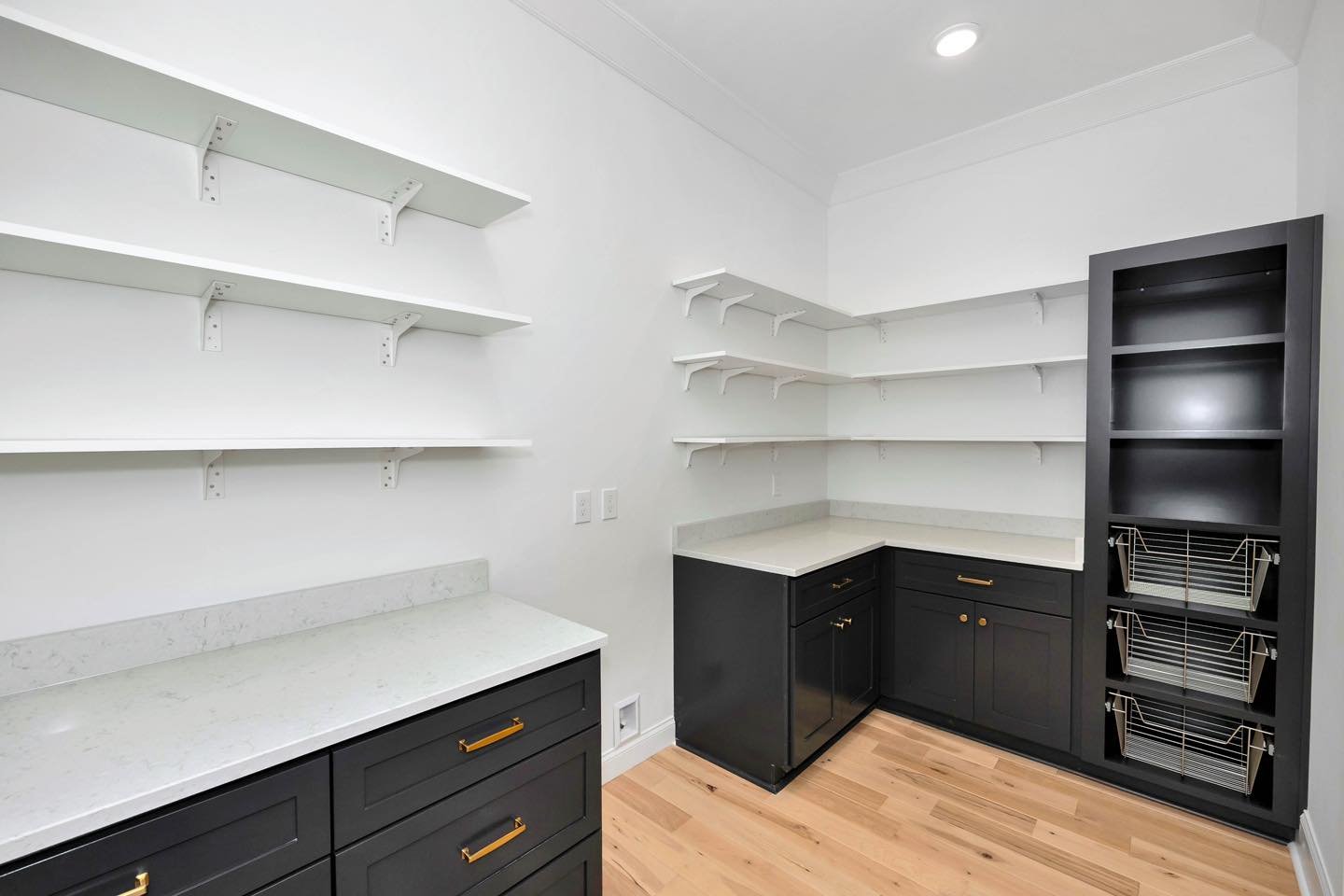 White wall-mounted laundry shelves on tracks and black tall cabinet with pull-out baskets