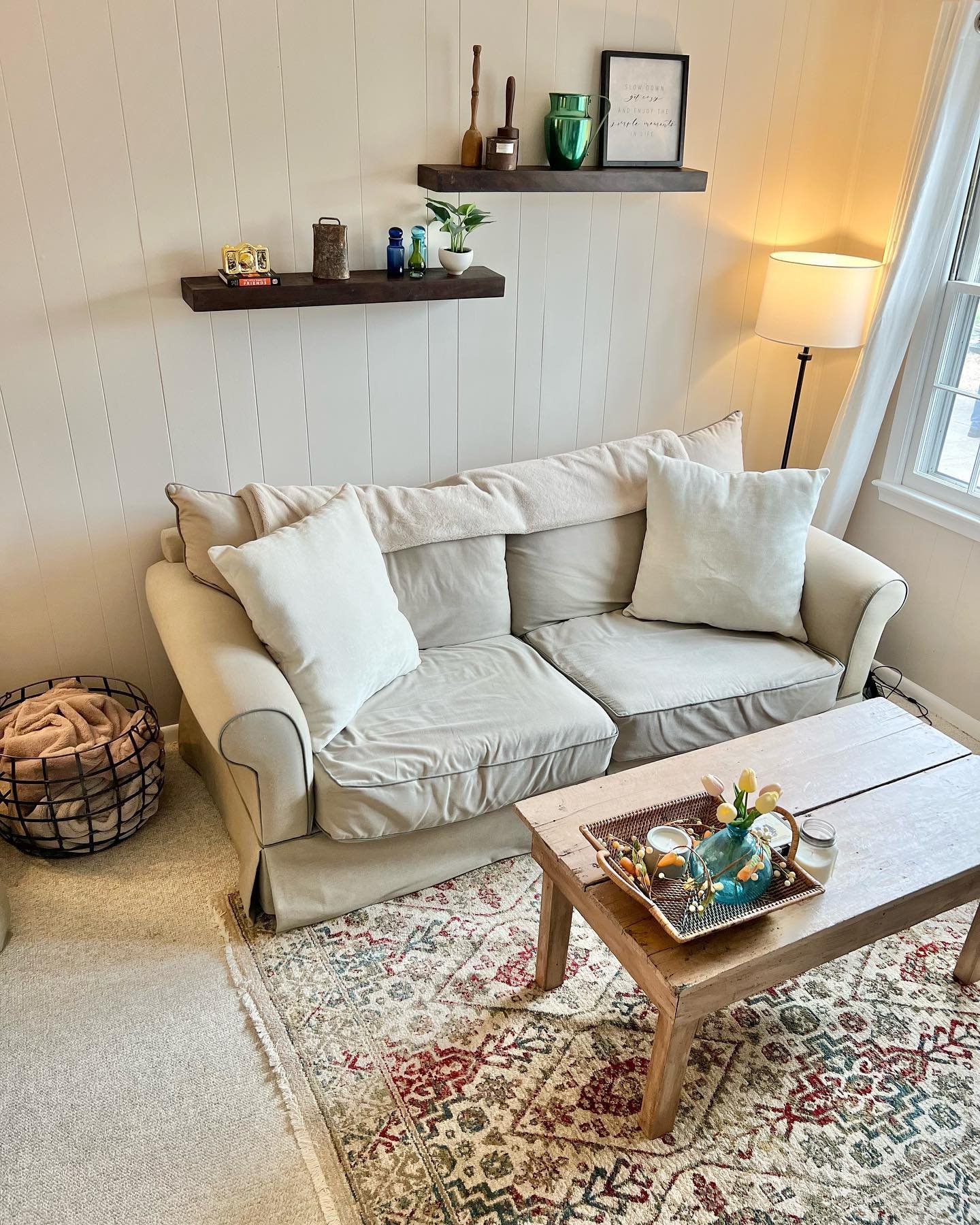 Dark floating shelves on a white shiplap wall displaying vintage green glass and decor