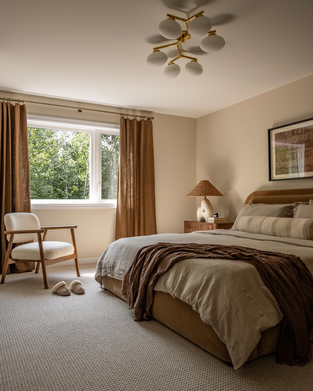 Beige bedroom featuring floor-to-ceiling brown curtains, a boucle accent chair, and a modern bubble chandelier