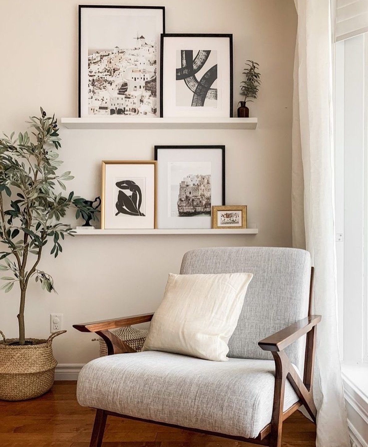 Two white floating picture ledges displaying layered framed art above an armchair
