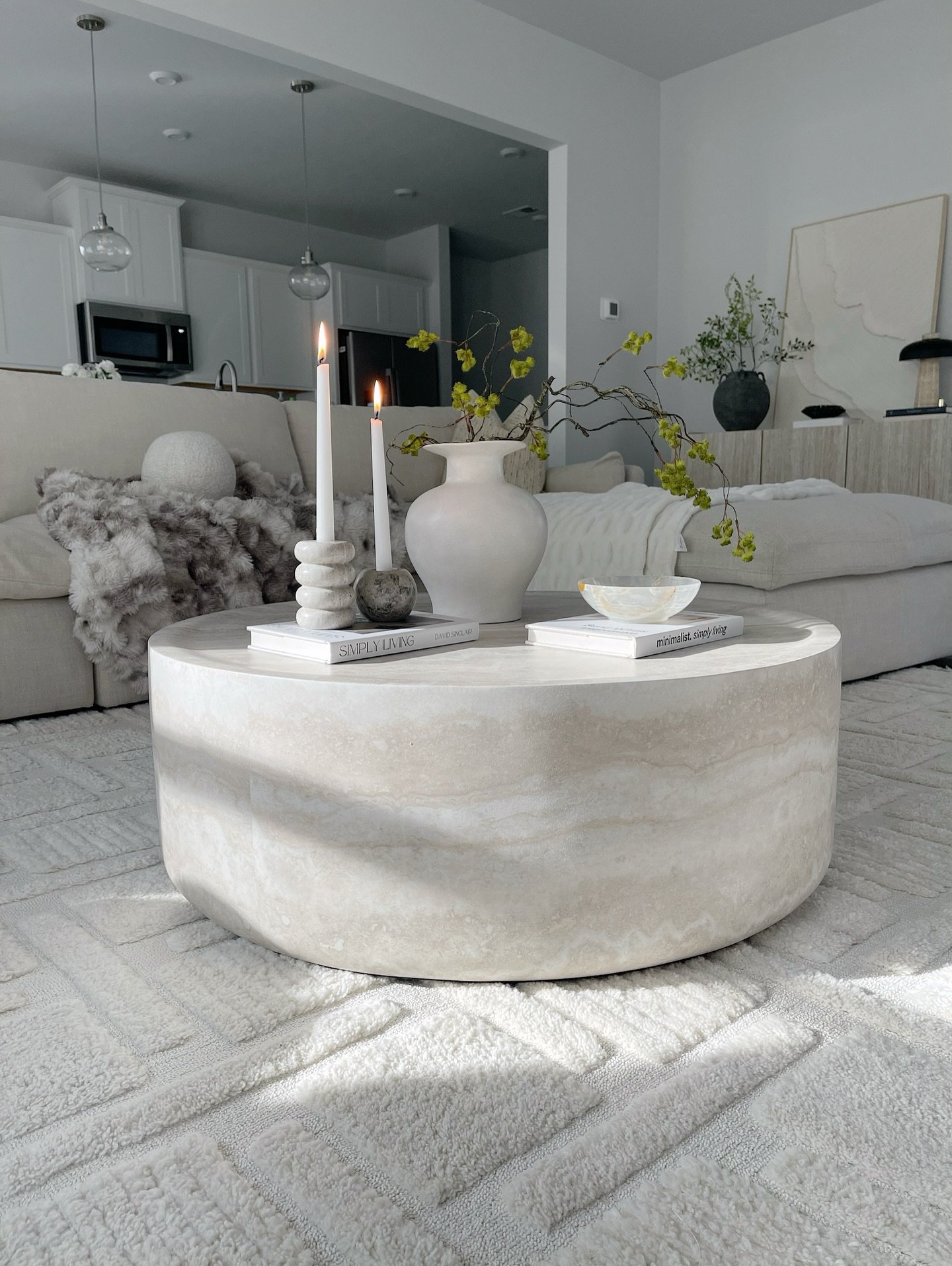 Round beige travertine coffee table with drum shape in a white living room