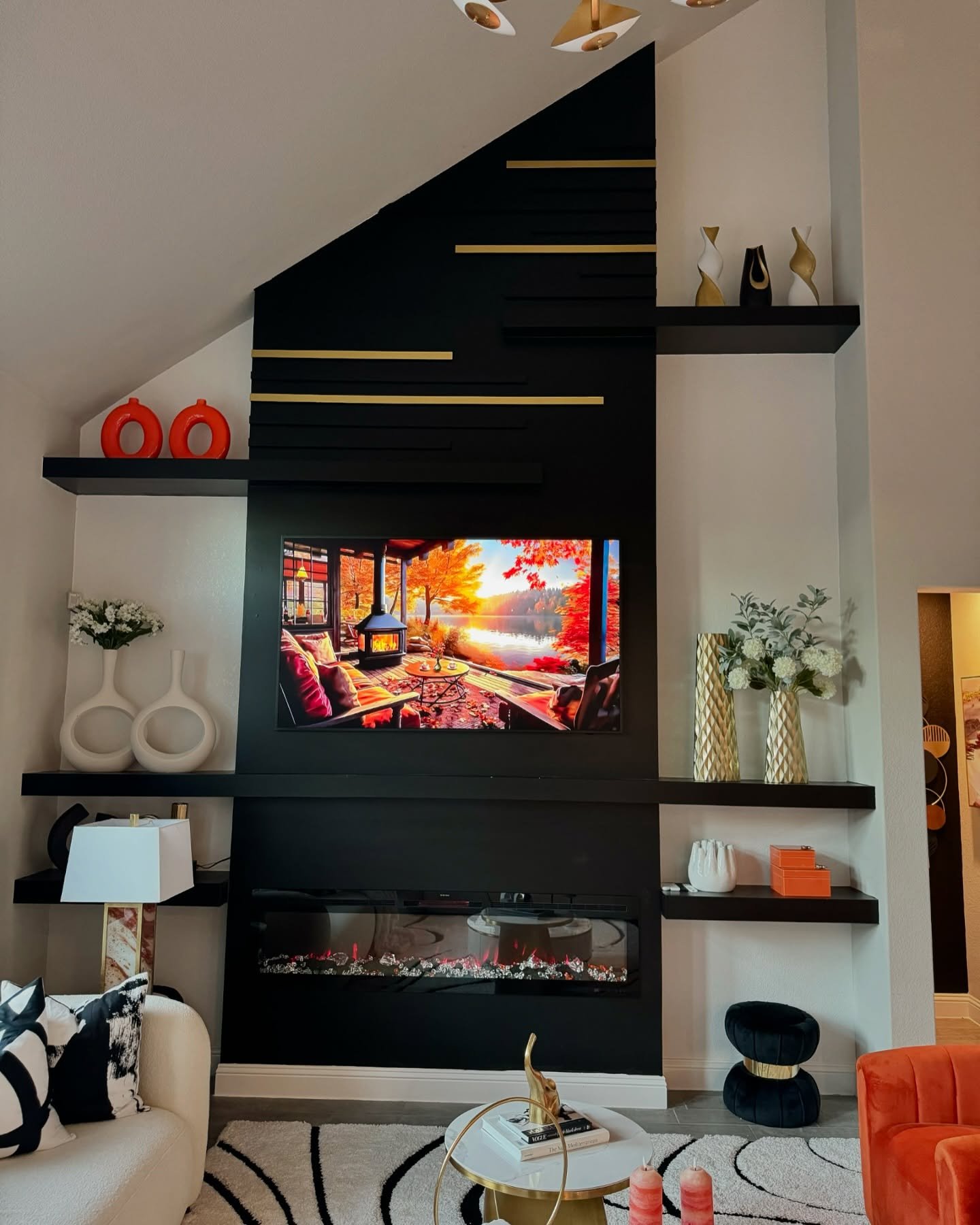 Black fireplace feature wall with asymmetrical floating shelves and gold accents under a vaulted ceiling.