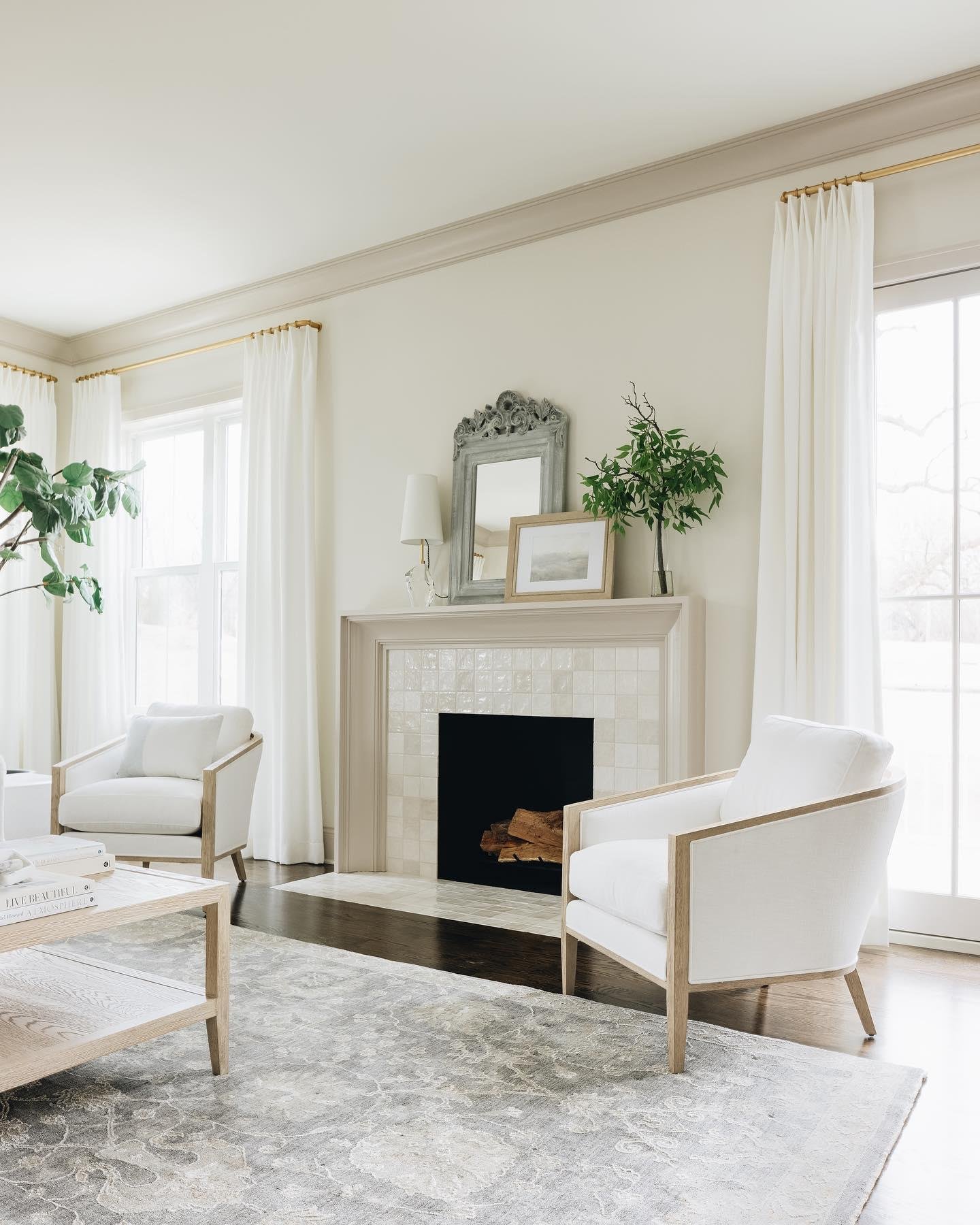 A neutral living room fireplace with a tan painted wood surround and a firebox lined with subtle, off-white square relief tiles.