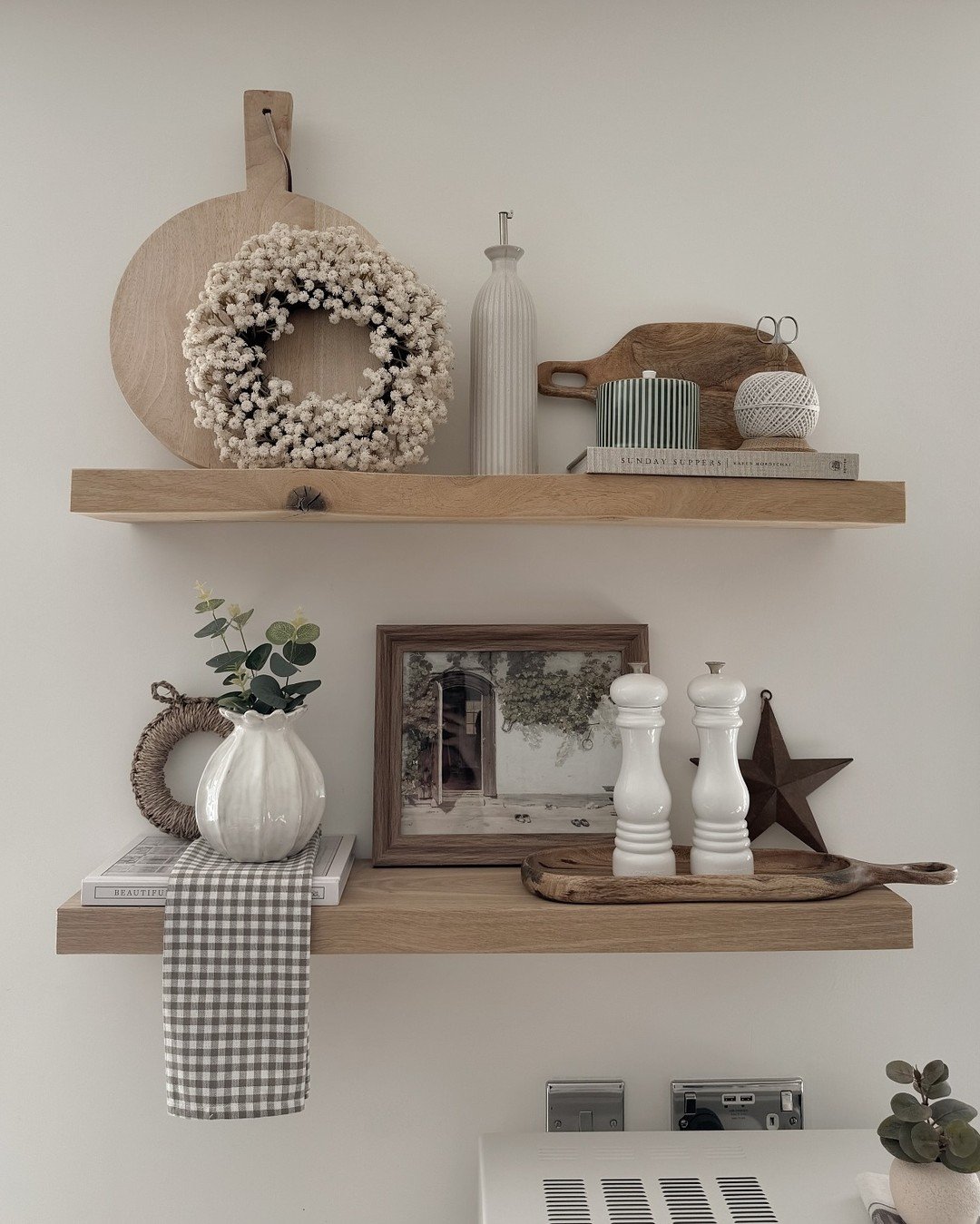Thick wooden floating shelves displaying rustic farmhouse decor items