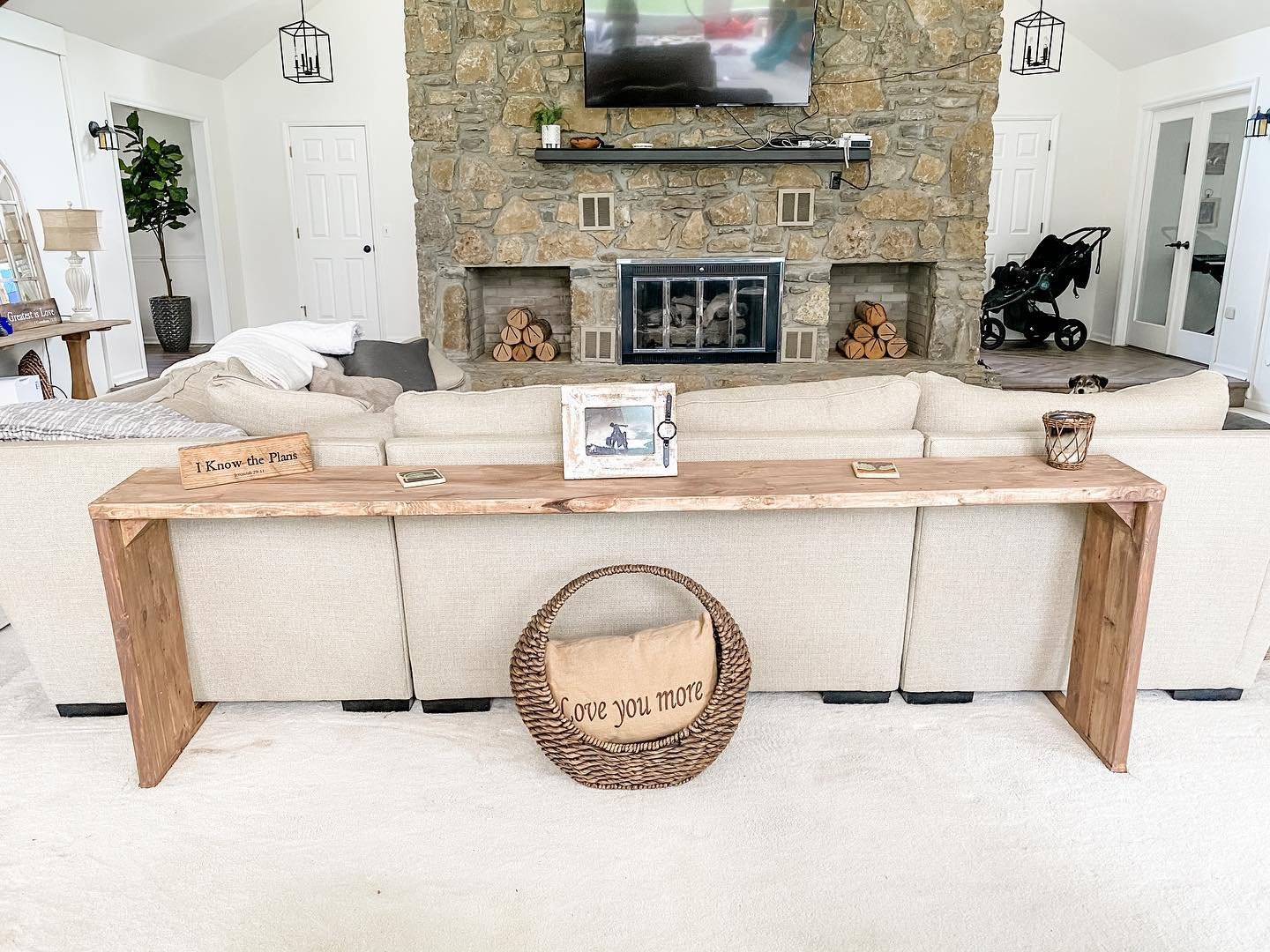 Very long narrow wooden console table behind a large sectional sofa