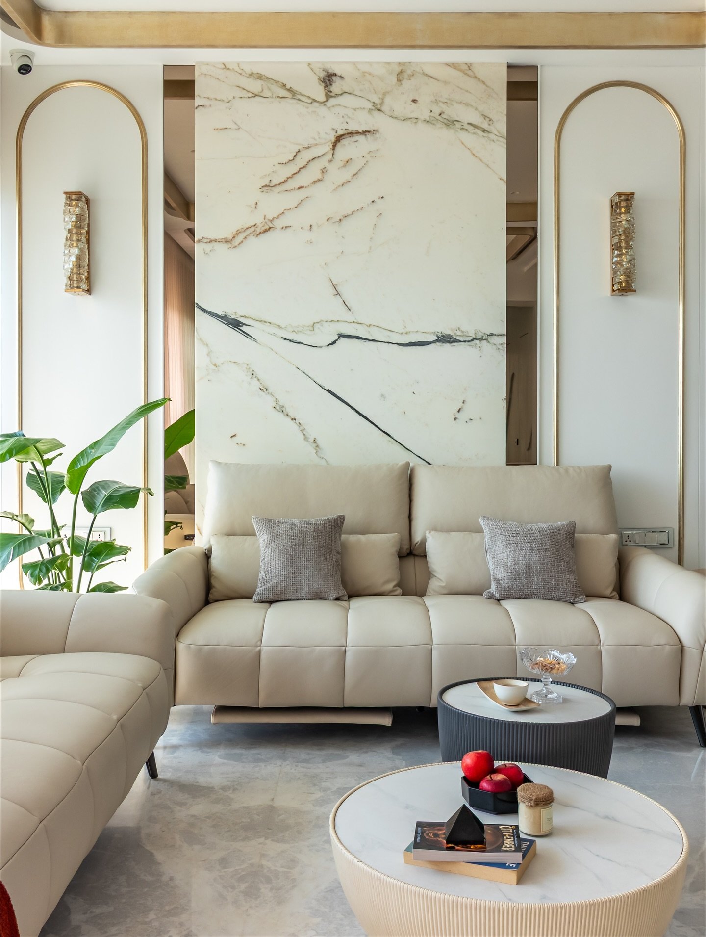 White marble slab accent wall flanked by gold arched molding and sconces