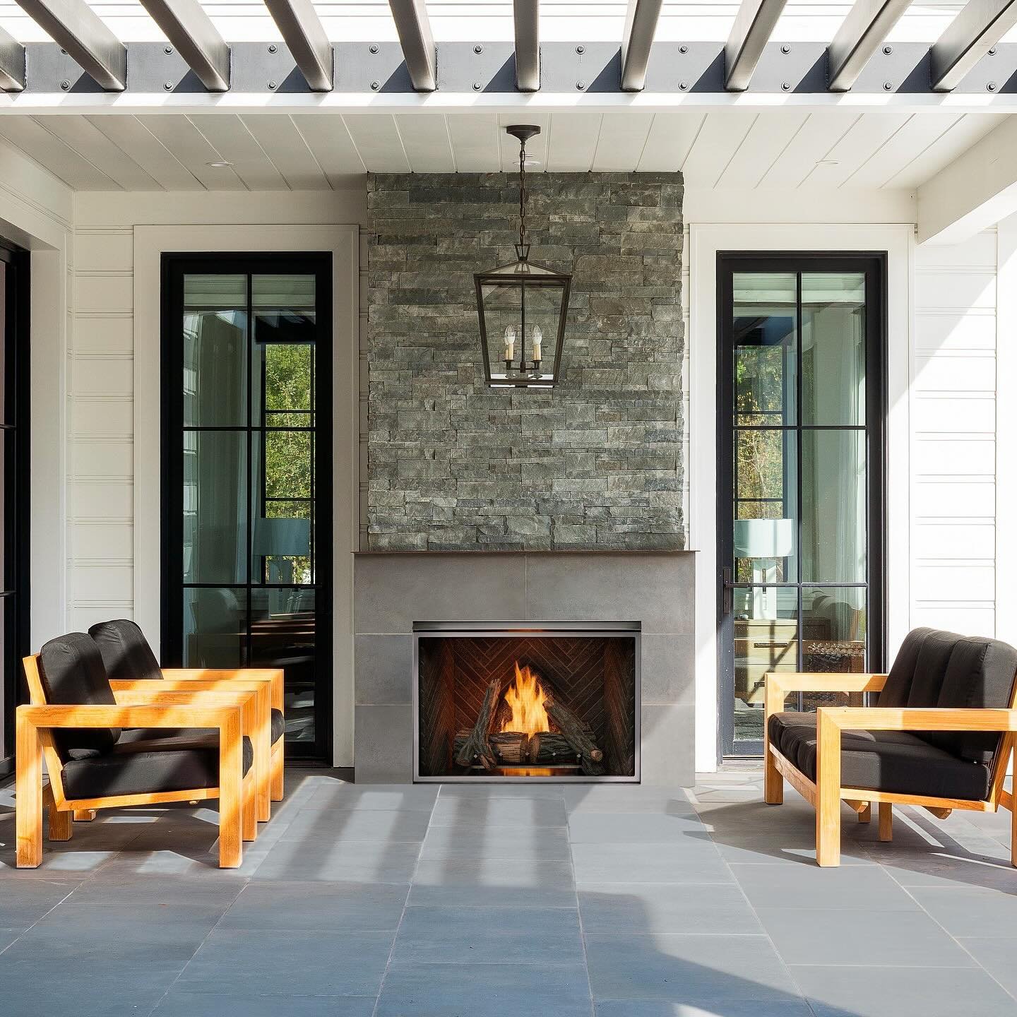 A contemporary outdoor gas fireplace with a light gray surround and a dramatic stacked gray slate accent wall above.