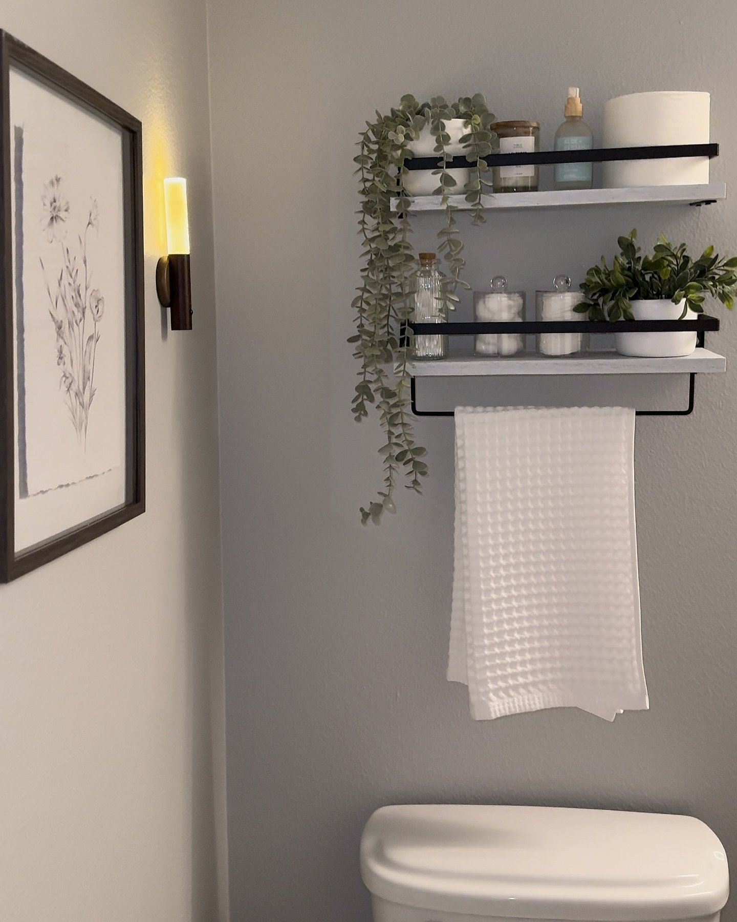 Bathroom grey wall decor featuring white floating shelves with black rails above toilet