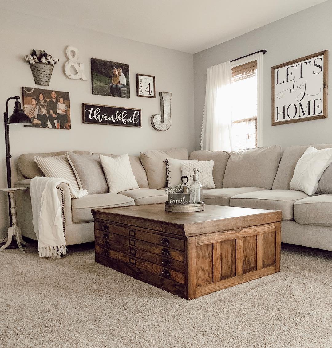 Gallery wall combining family photos, rustic wooden signs, and metal letters above a corner sectional sofa.