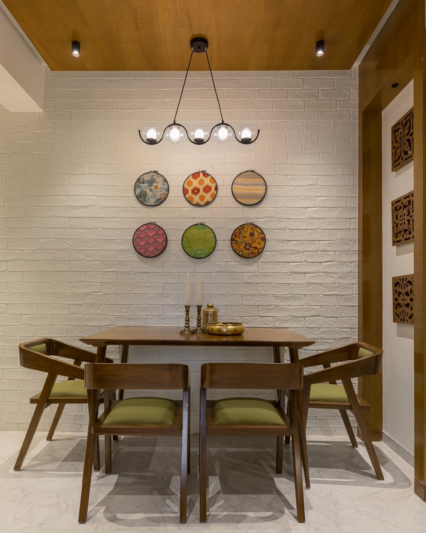 White brick dining wall featuring colorful circular fabric art and modern lighting
