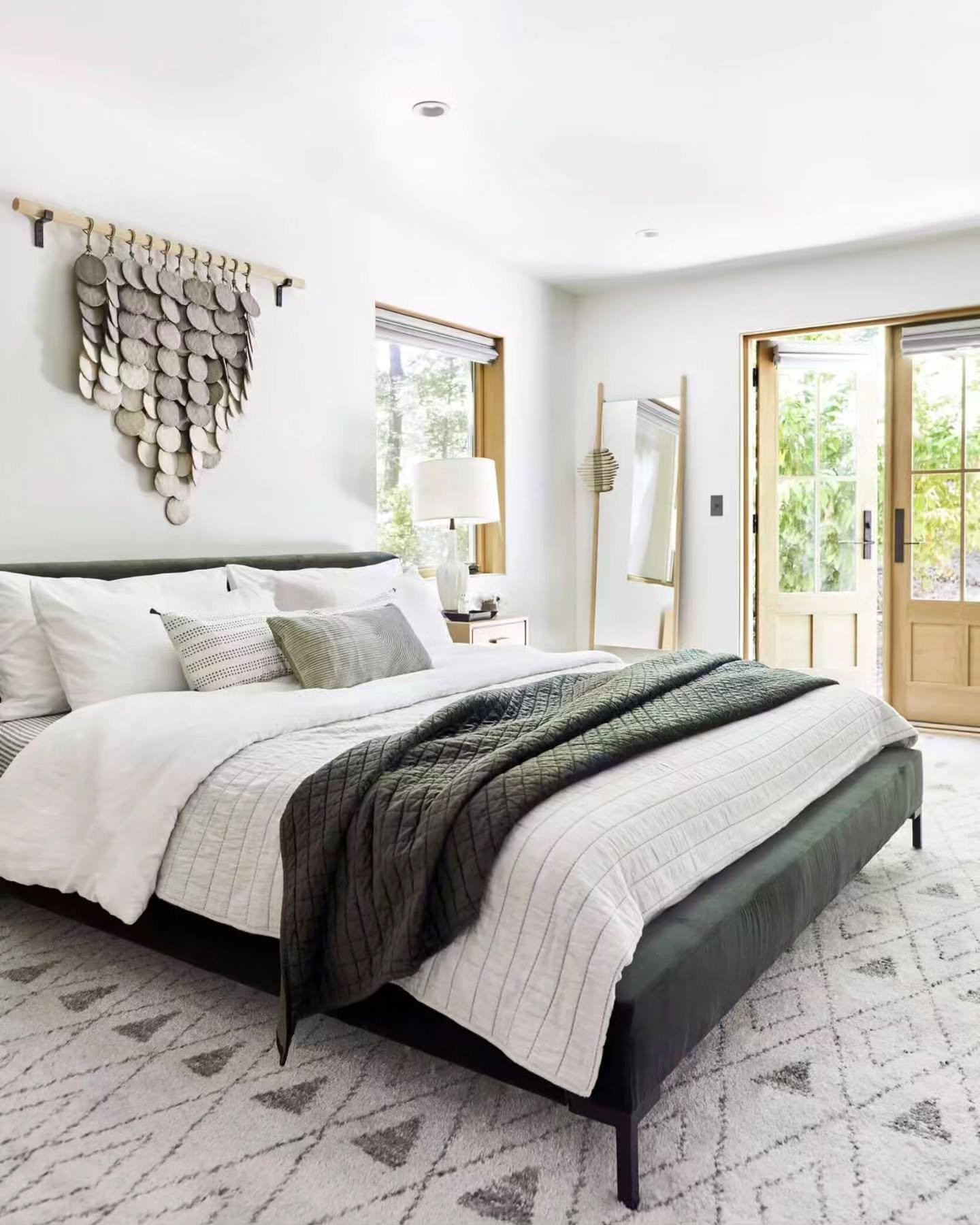 Bright bedroom featuring a large silver metallic disc wall hanging above the bed