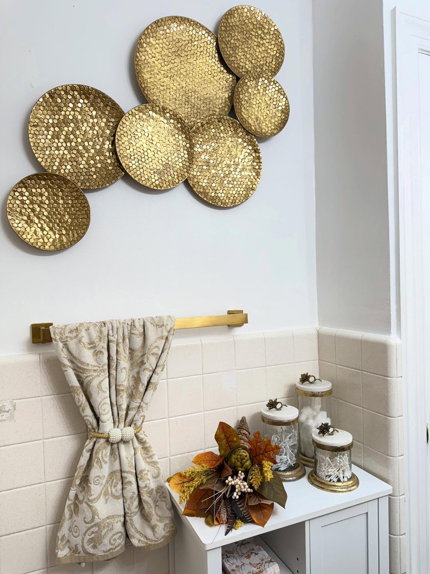 Bathroom wall decor featuring hammered gold metal circles on white paint