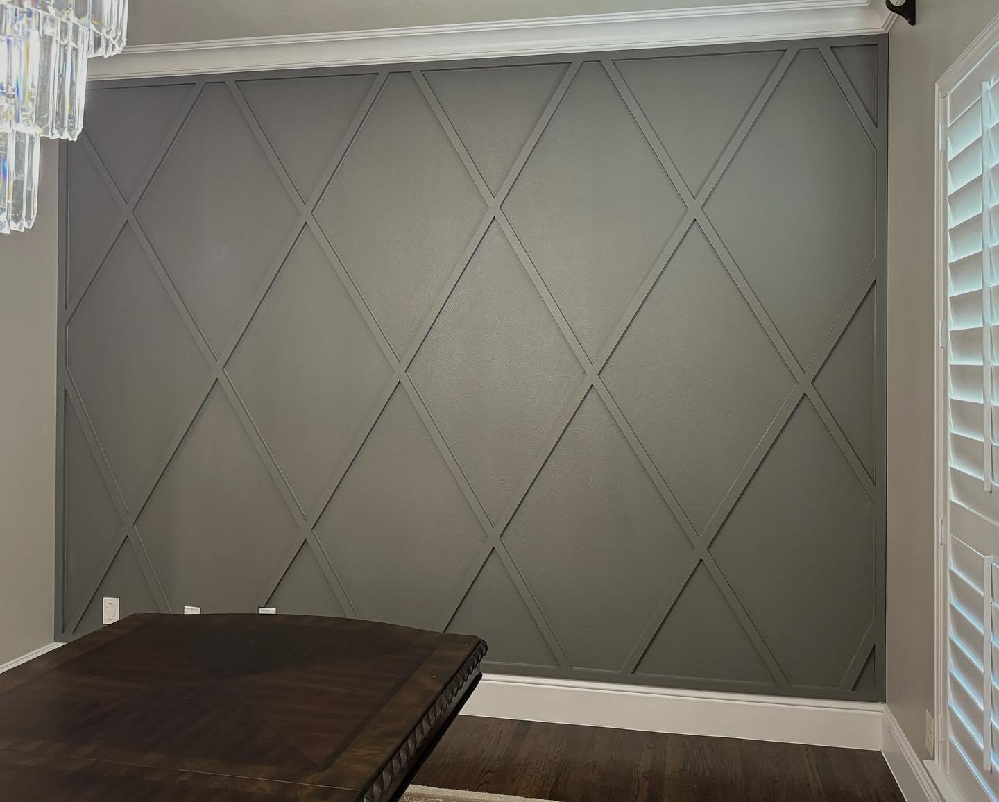 Dark gray dining room accent wall featuring diamond lattice molding and white crown molding.