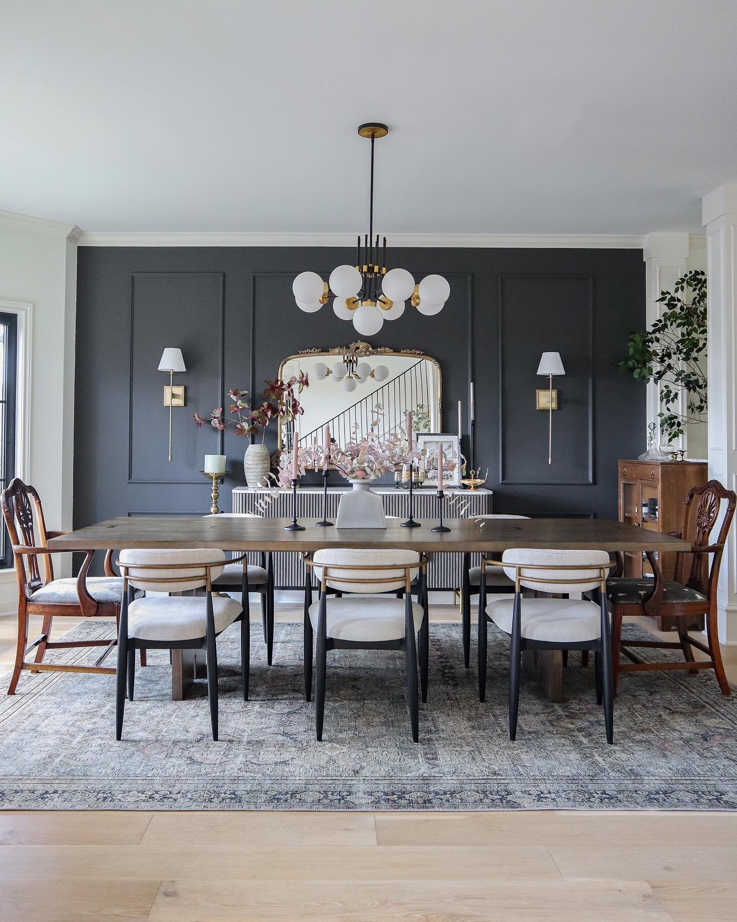 Dark charcoal dining room wall with panel molding and large gold mirror