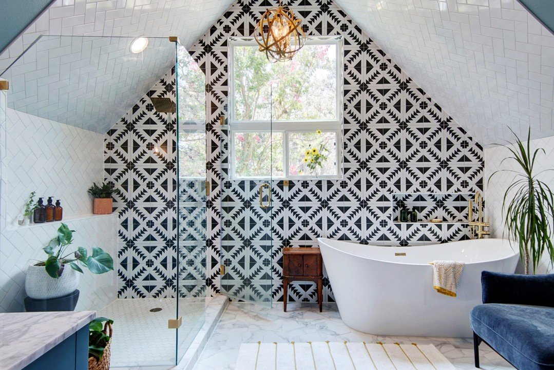 Attic bathroom with black and white geometric tiles, white tub, and gold sphere light.