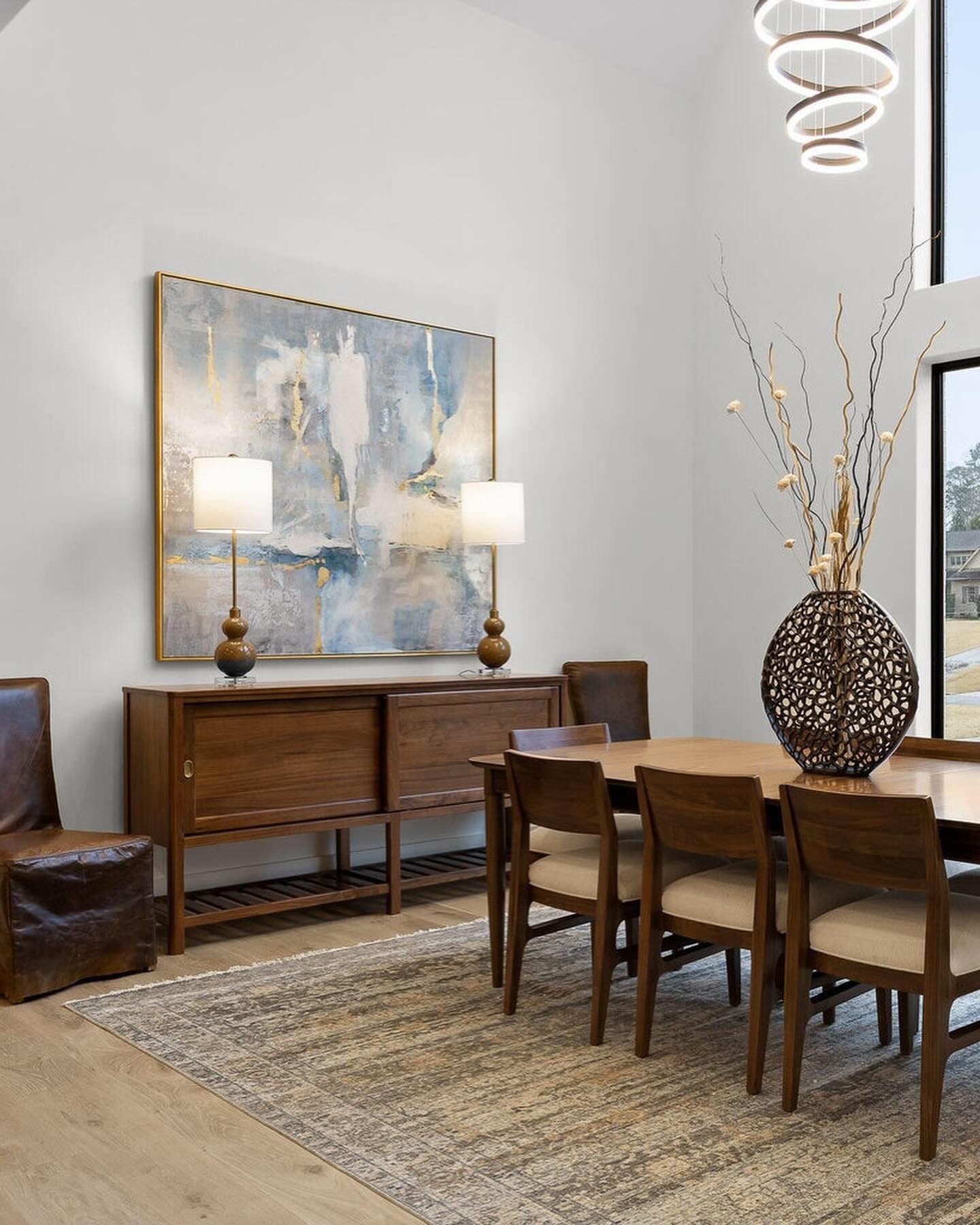 Airy dining room featuring large blue and gold abstract art above a wooden console