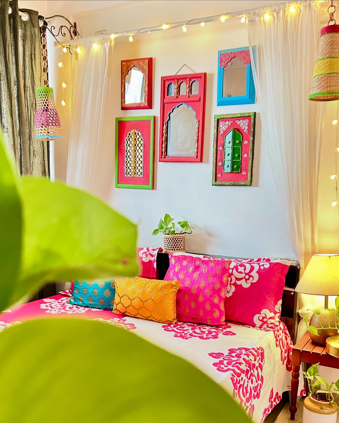 White bedroom wall decorated with colorful Indian Jharokha frames and hanging lanterns