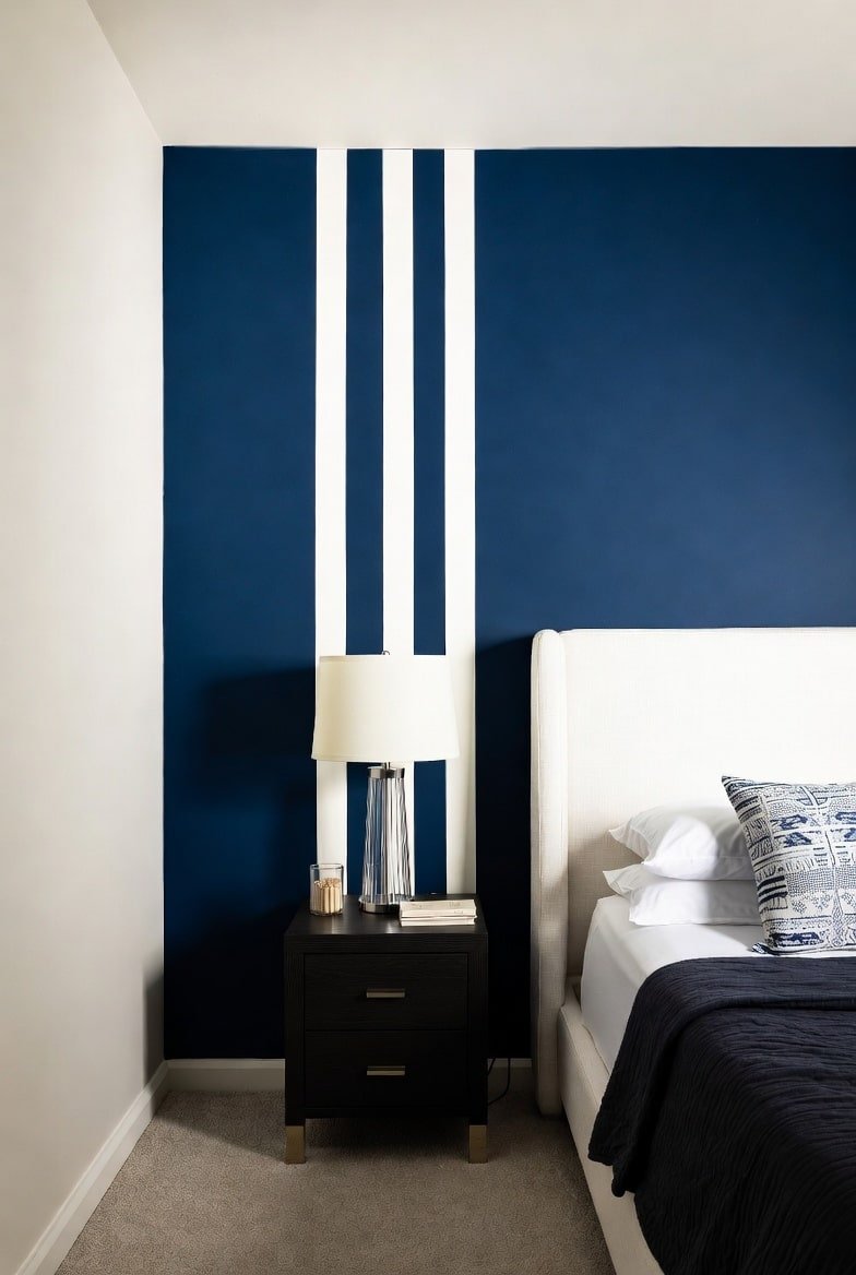 Navy blue accent wall with three white vertical painted stripes behind nightstand