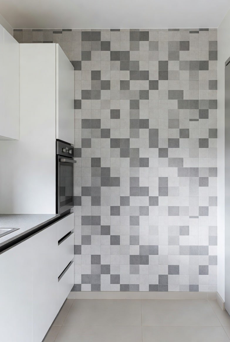 Kitchen featuring a floor-to-ceiling grey and white pixelated tile accent wall