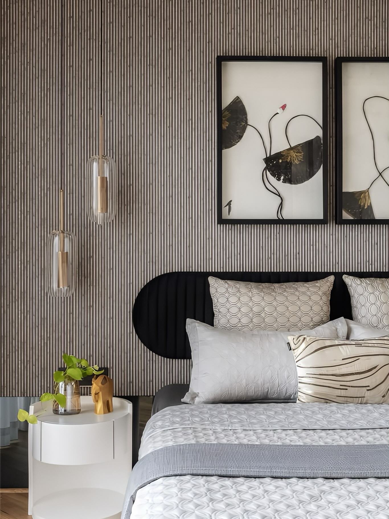 Bedroom accent wall with vertical striped wallpaper, black headboard, and two botanical art prints