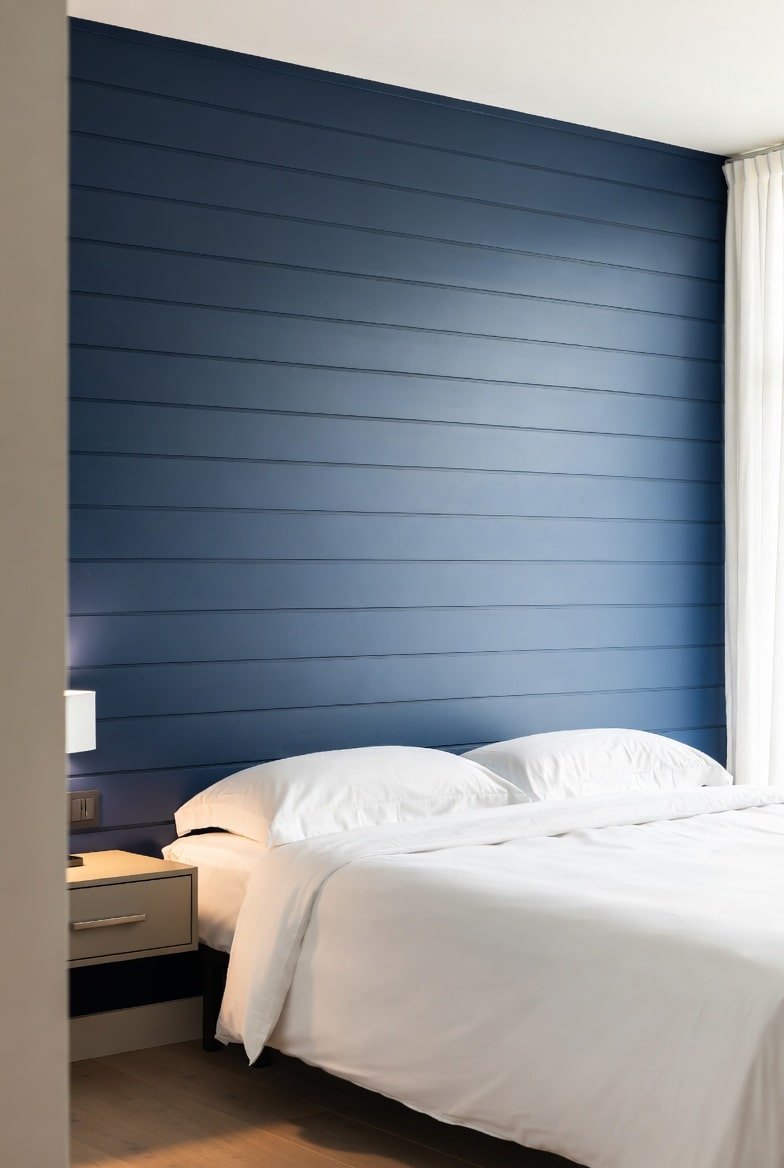 Navy blue horizontal shiplap accent wall behind white minimalist bed