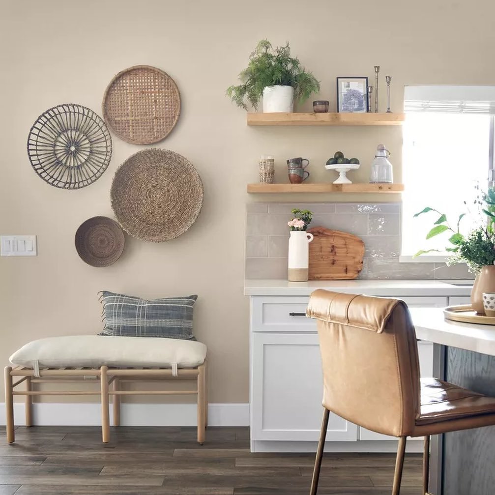 Kitchen wall decorated with a cluster of round woven baskets above a cushioned bench