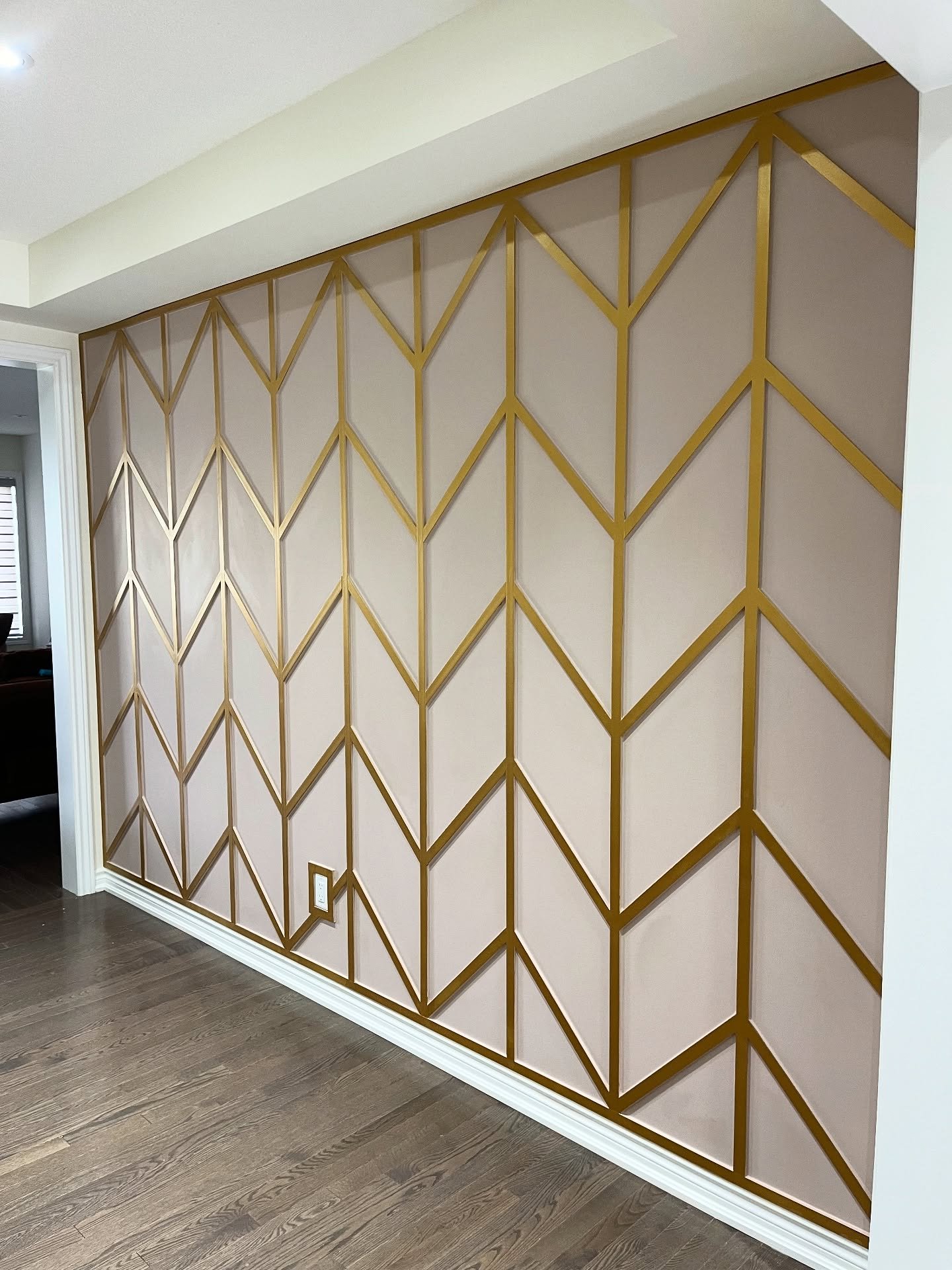 Blush pink dining room accent wall featuring gold chevron molding strips.