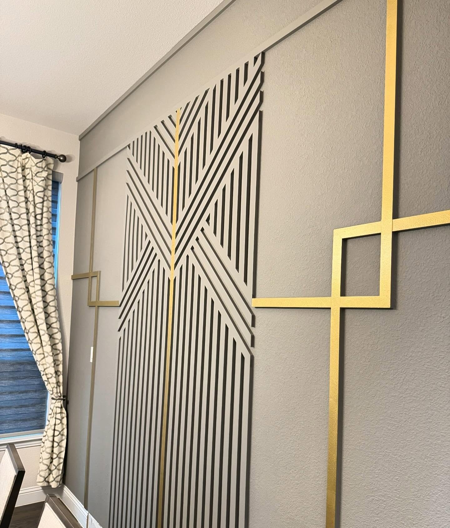 Gray dining room accent wall featuring abstract gold geometric molding and patterned curtains.