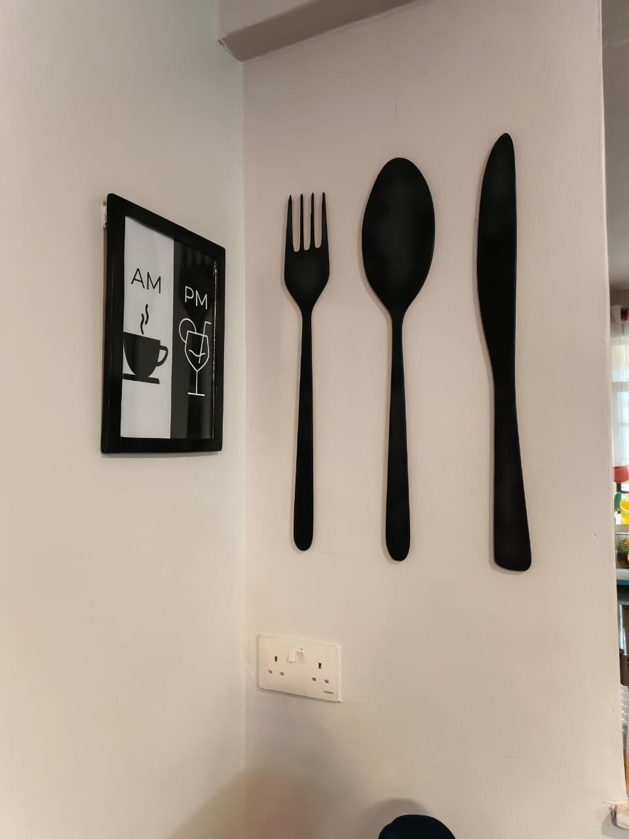 Kitchen wall featuring large black fork spoon and knife wall art next to a coffee wine print
