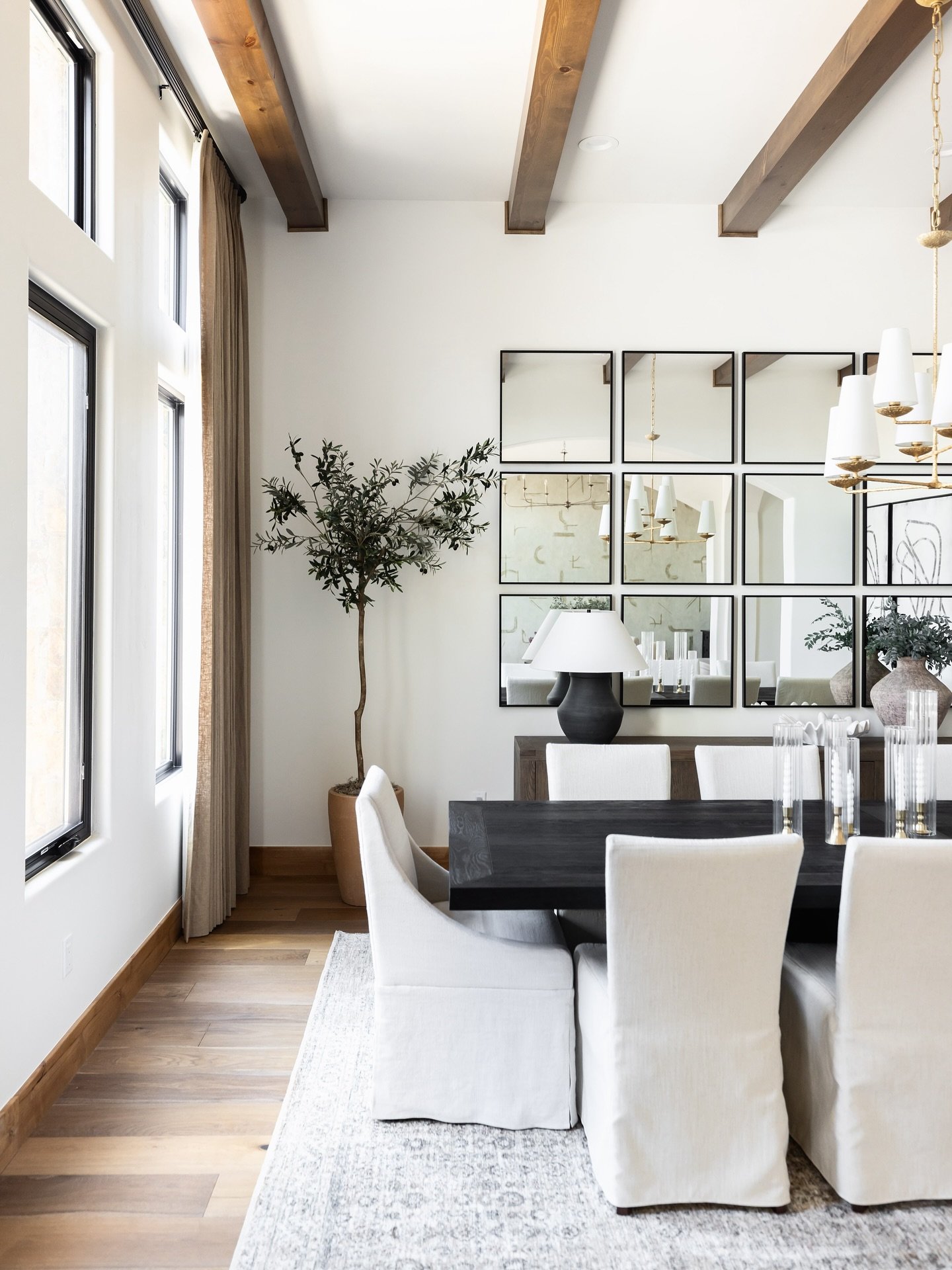 Bright dining room featuring a grid of square black-framed mirrors on a white wall