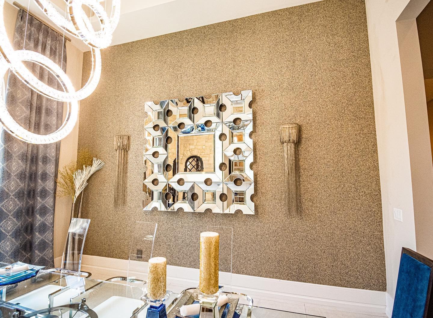 Gold textured glitter accent wall in a dining room featuring a geometric mirror and crystal chandelier.