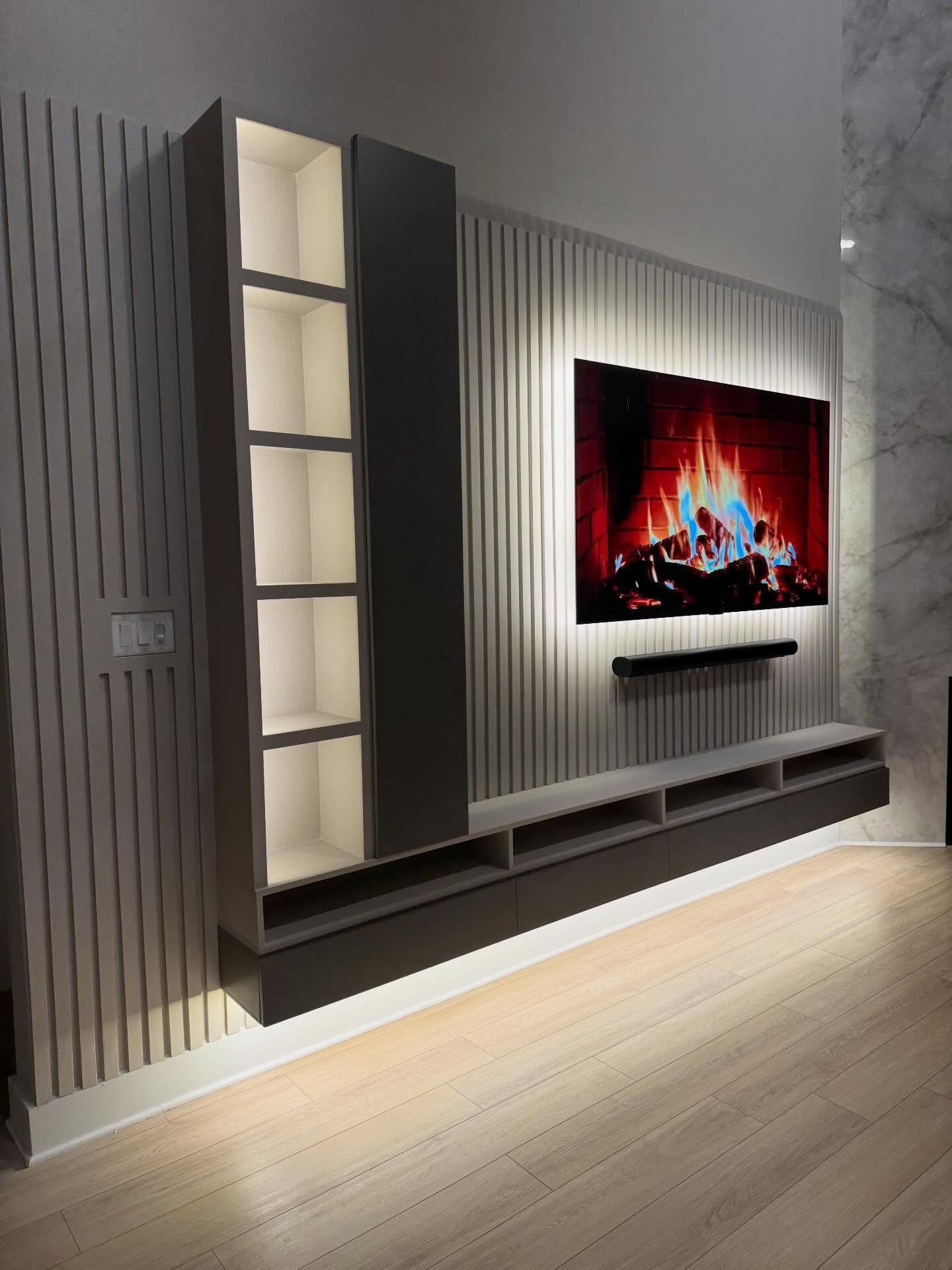 Grey vertical slat TV wall with built-in lighted shelves and floating console.