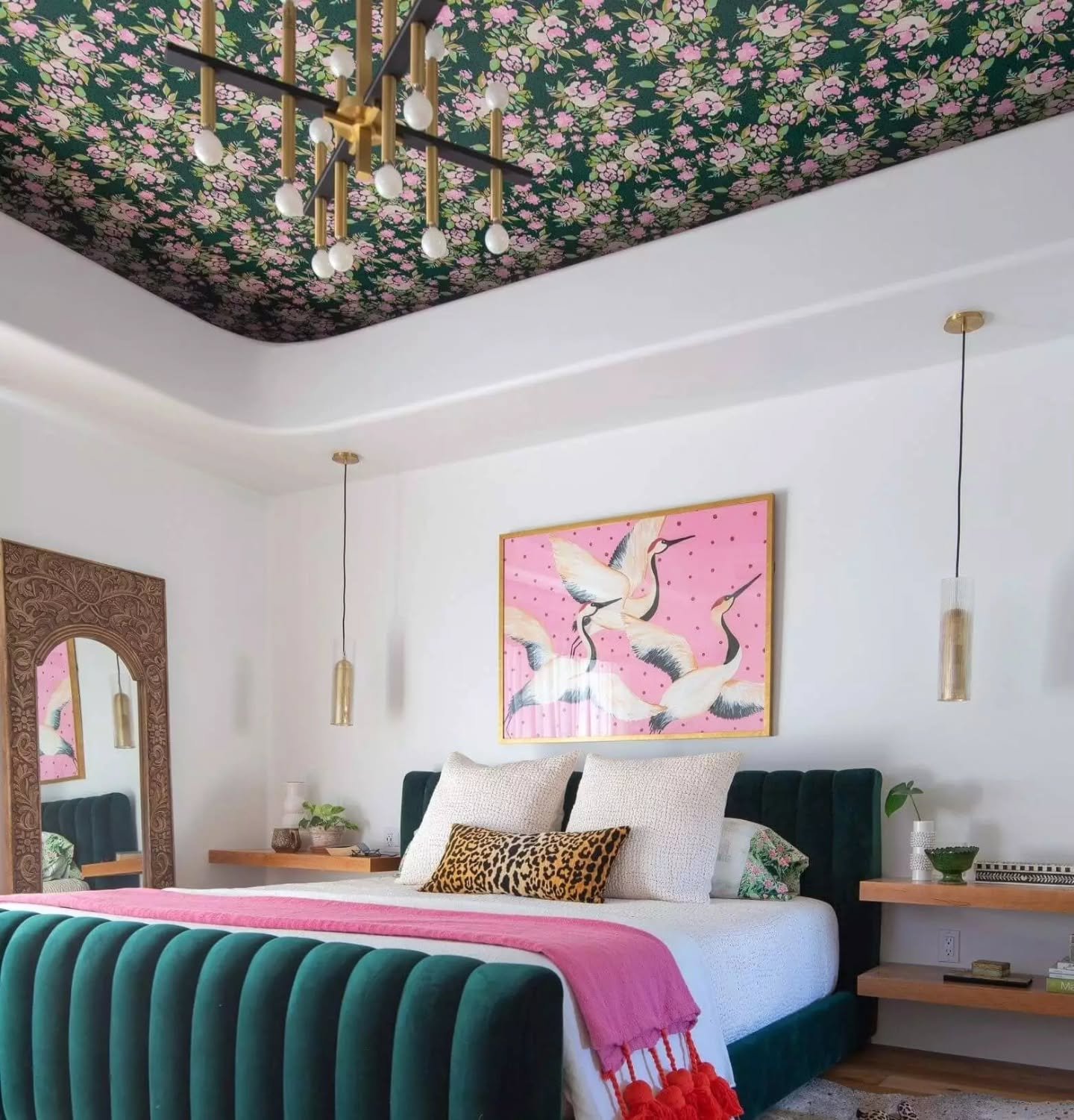 White bedroom wall decorated with large framed pink bird artwork and gold accents