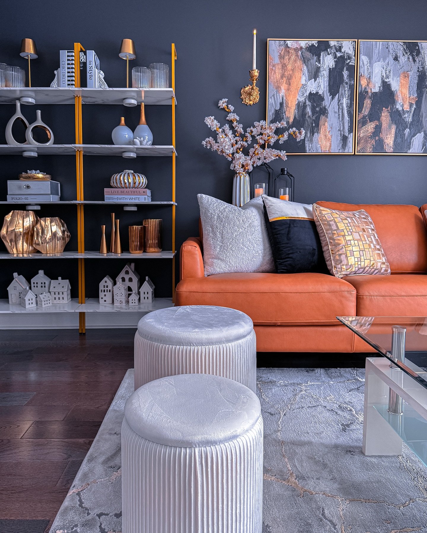 Dark grey accent wall featuring abstract copper artwork above an orange leather sofa.