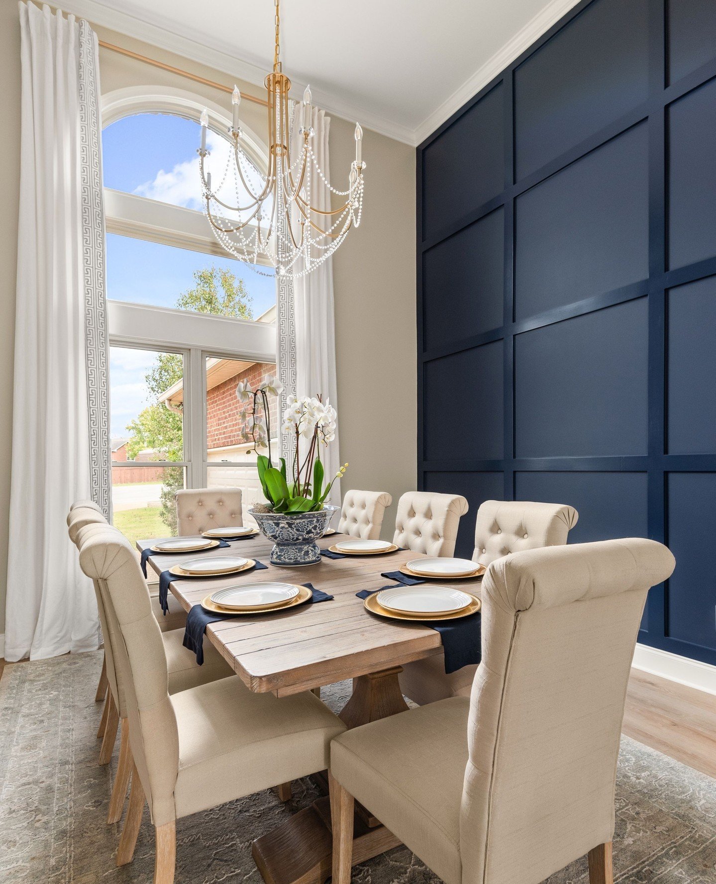 Navy blue board and batten accent wall in a dining room with high ceilings.