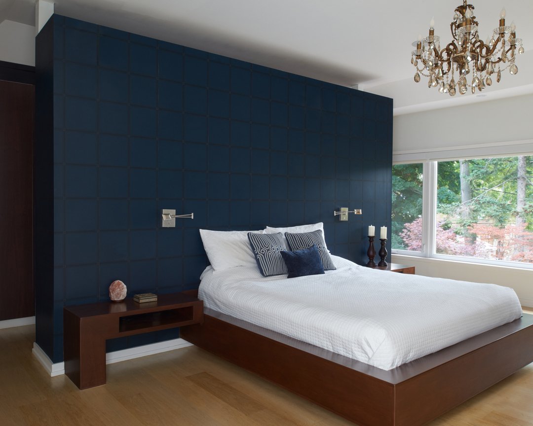 Navy blue grid textured partition wall behind dark wood platform bed