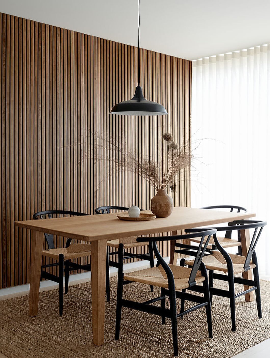 Dining room featuring a floor-to-ceiling vertical wood slat accent wall behind a wooden table.